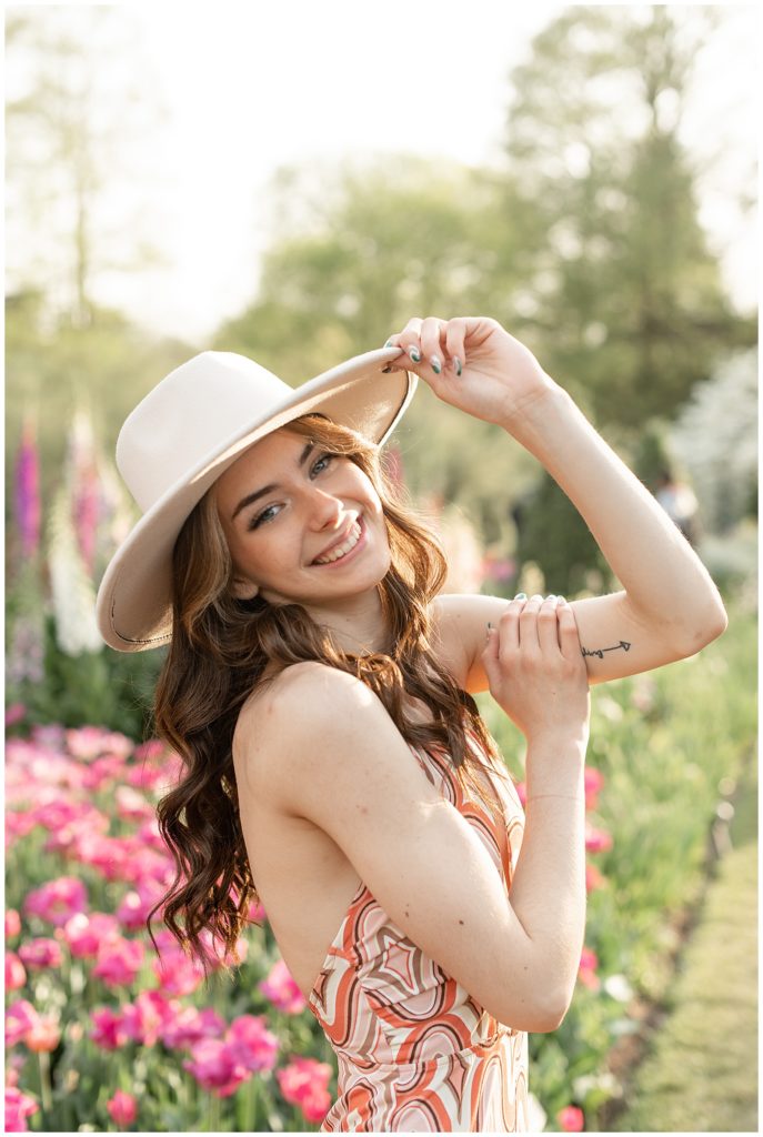 senior girl with right shoulder toward camera holding brim of her trendy hat with left hand in lancaster pennsylvania