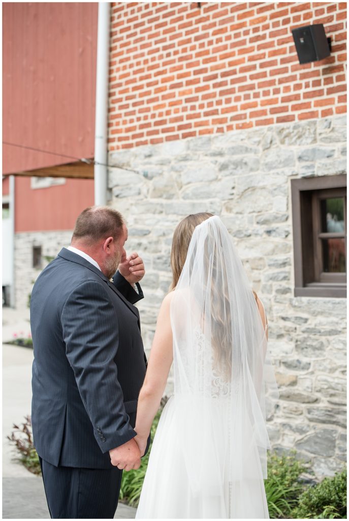 bride and her father cry as they share a first look outside the barn at brick gables on a cloudy day