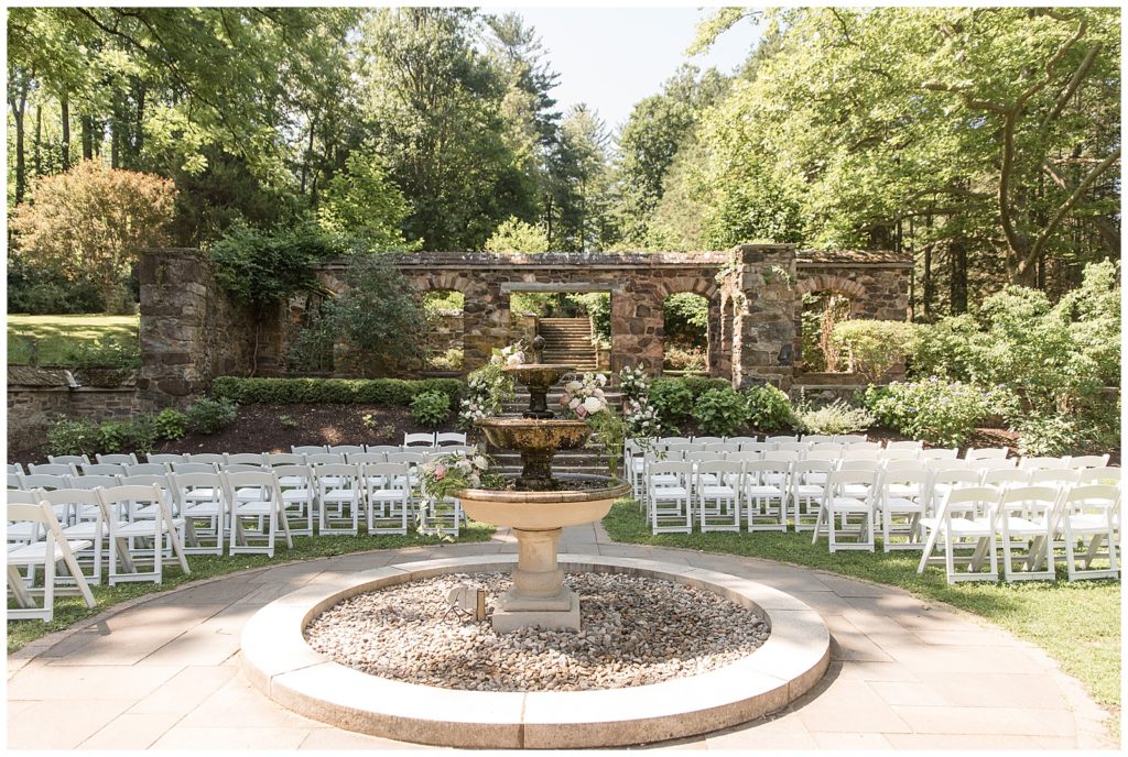 beautiful water fountain at the center of outdoor wedding ceremony with rows of white chairs behind it at parque ridley creek