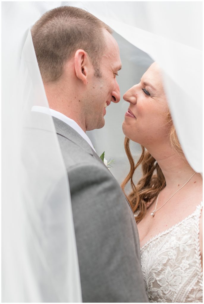 bride and groom almost kissing as her long white veil surrounds them at elizabeth furnace in lancaster pennsylvania