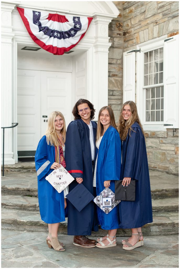 three female and one male senior spokesmodels in their blue graduation gowns holding their graduation caps and smiling by historic building in lititz pennsylvania