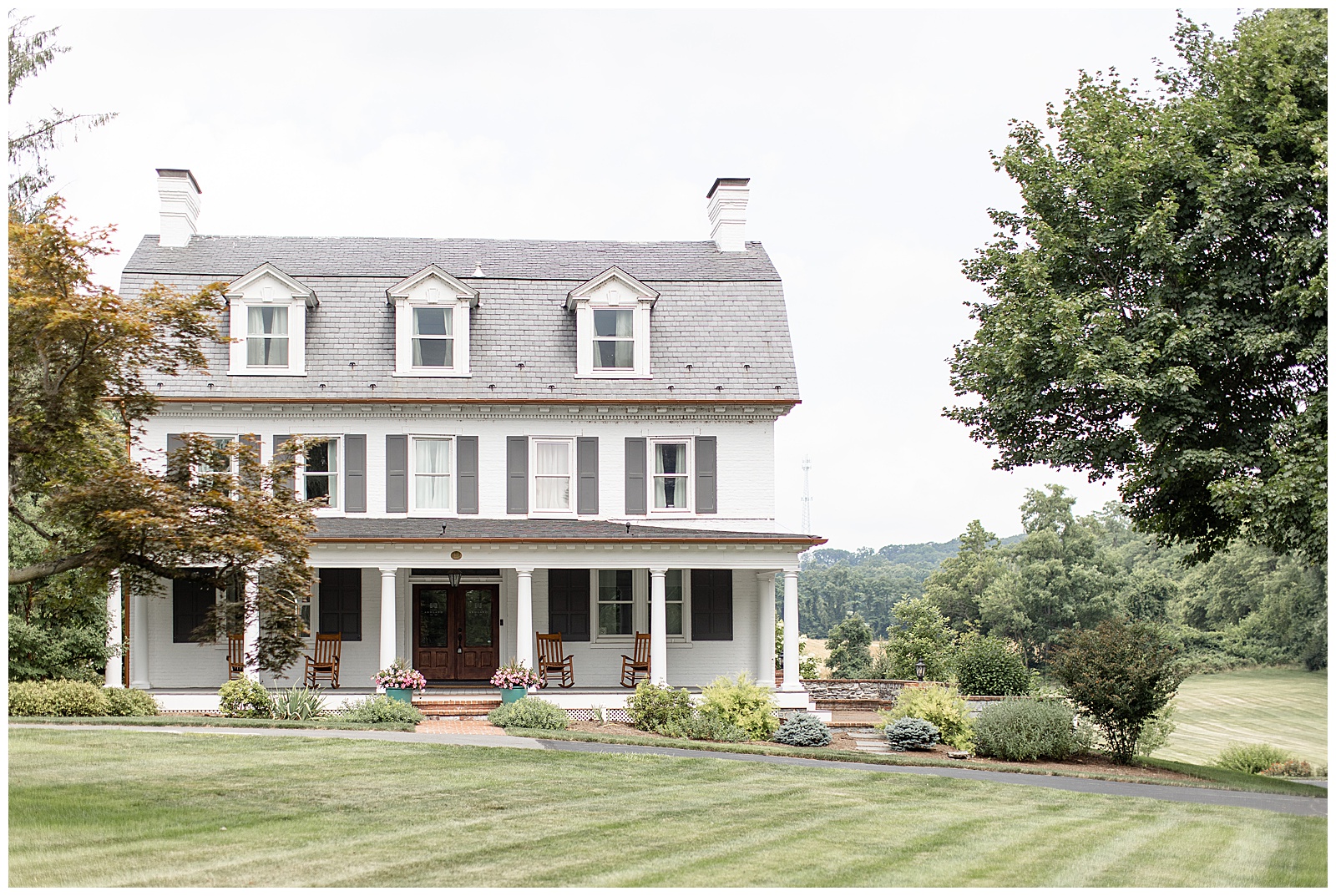 historic white farmhouse with gray shutters and beautiful manicured lawn and flowerbeds at historic ashland