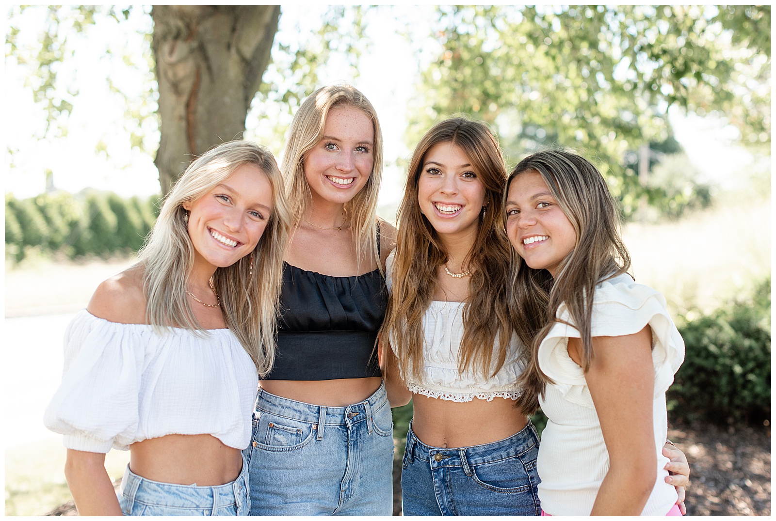 four senior girls with arms around each other smiling on sunny day in lancaster pennsylvania