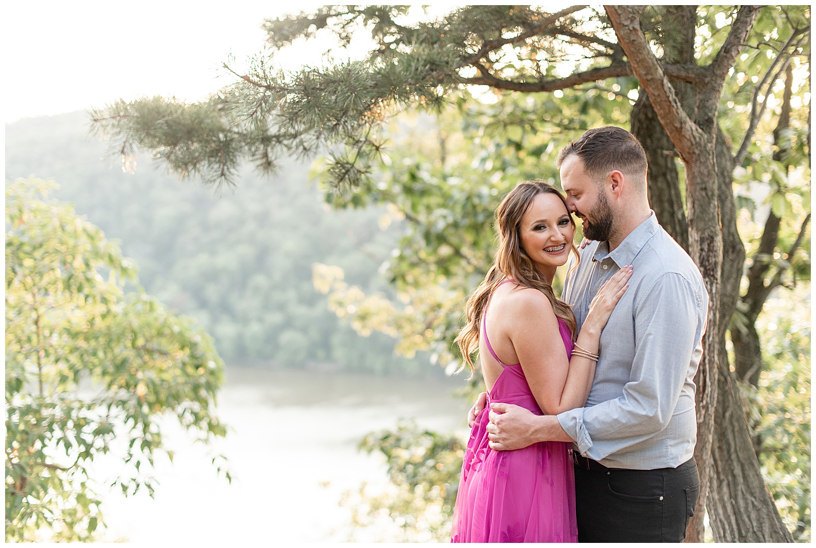 engaged couple hugging as woman smiles at camera leaning against her man by river at pinnacle point