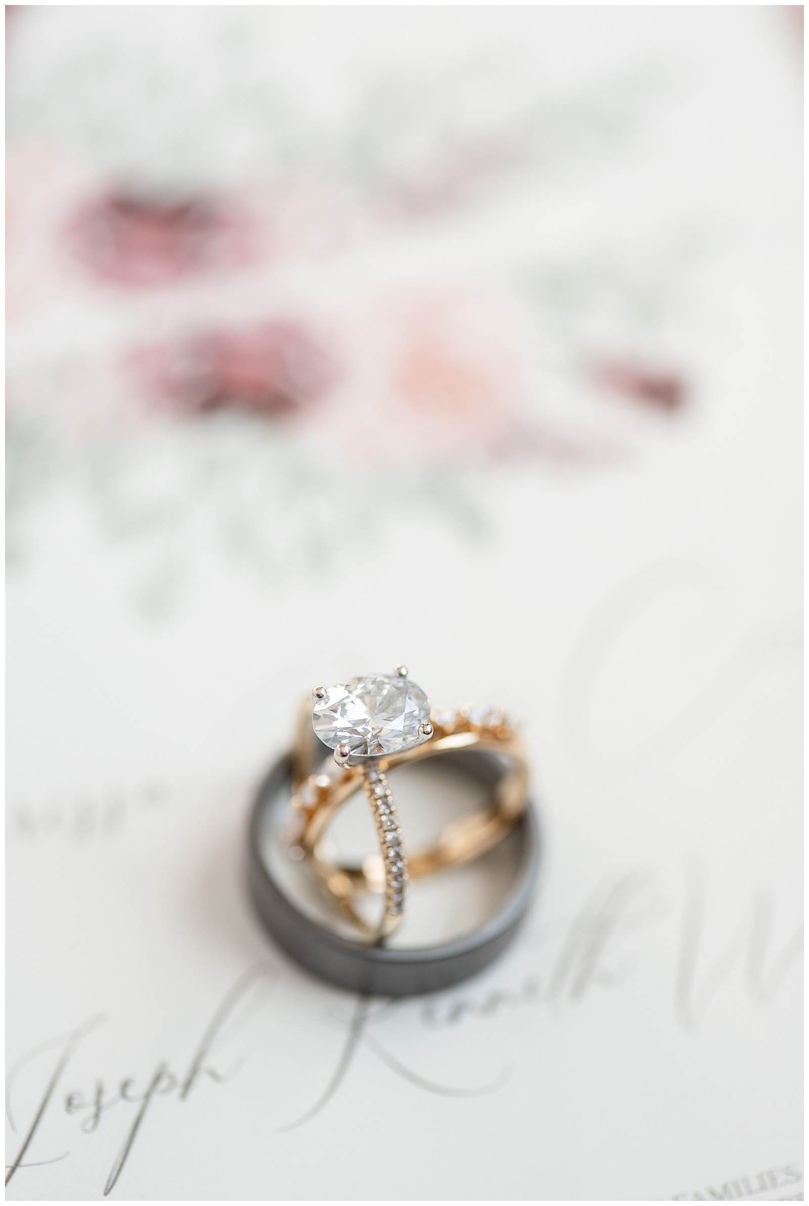 bride's gold diamond wedding and engagement rings resting inside groom's dark gray wedding band at folino estate
