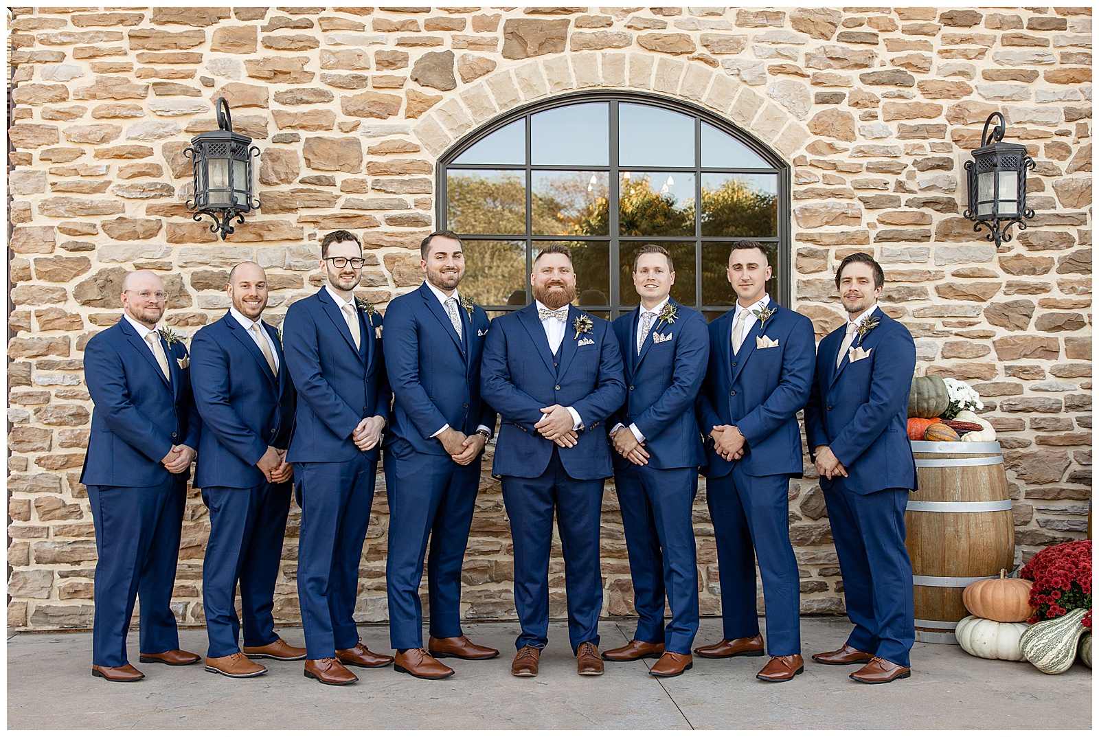 groom standing with his six groomsmen and all wearing navy blue suits outside stone building at folino estate