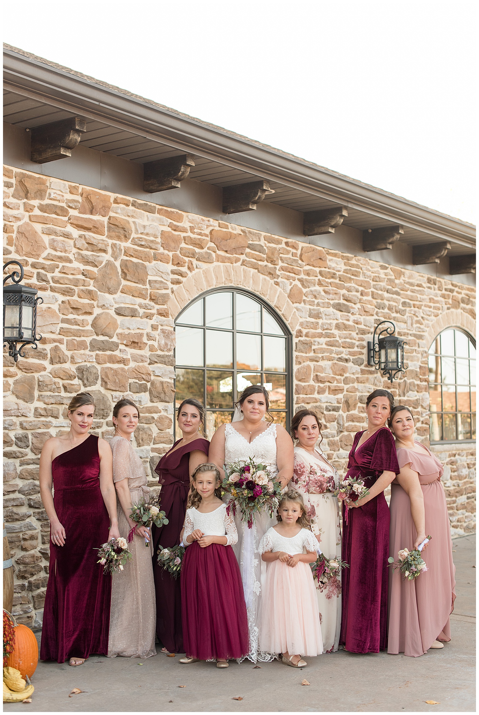 bride and her bridesmaids posing with their backs toward each other by stone building at folino estate
