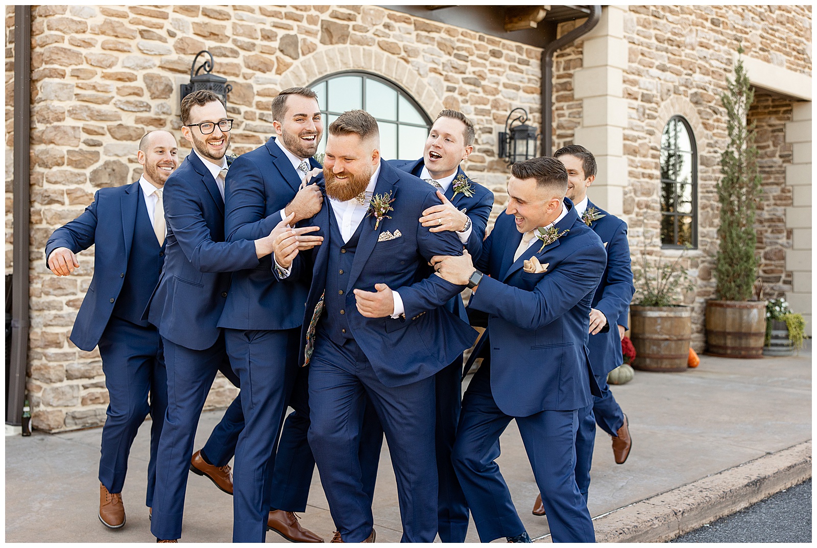 groomsmen huddled around groom with high energy as they all smile and laugh at folino estate in kutztown pennsylvania