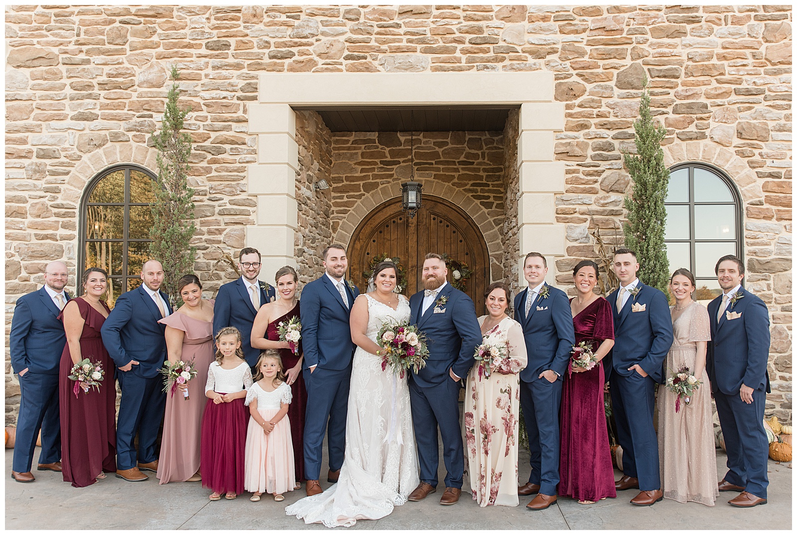 couple surrounded by their bridal party outside beautiful stone building at folino estate in pennsylvania
