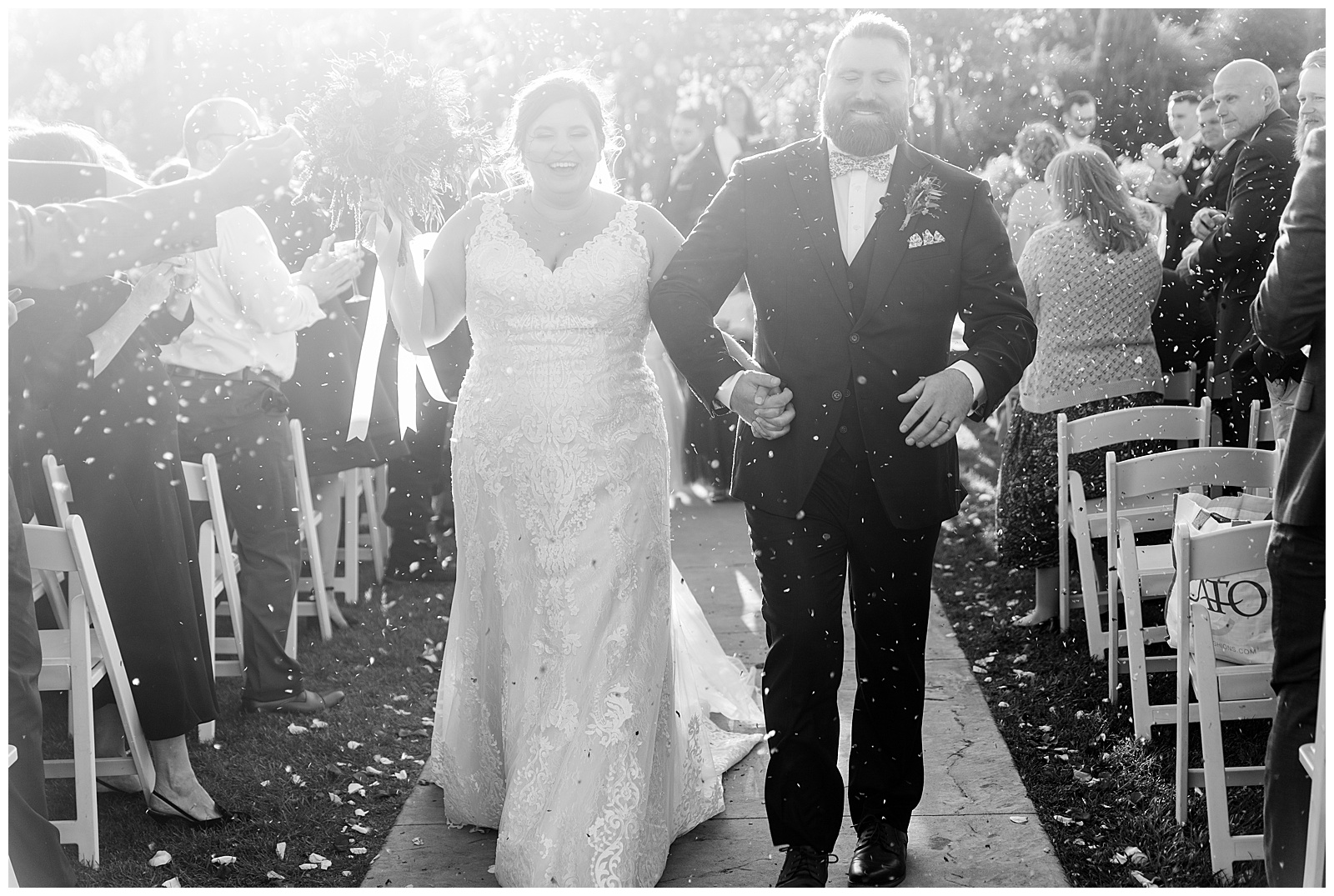 black and white photo of couple exiting their outdoor wedding ceremony with huge smiles on sunny day at folino estate