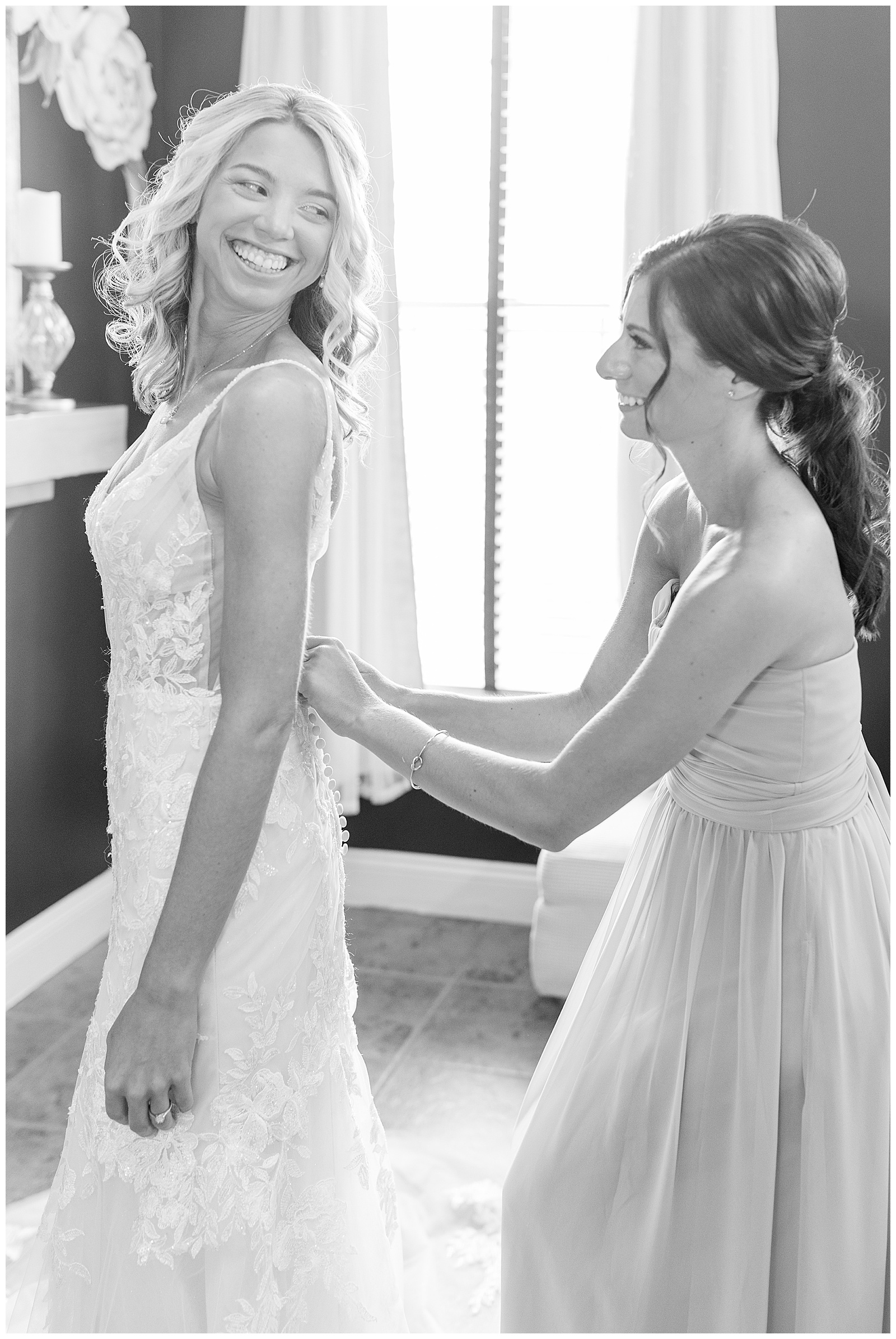 black and white photo of maid of honor helping with back of bride's gown in bridal suite at the links at gettysburg