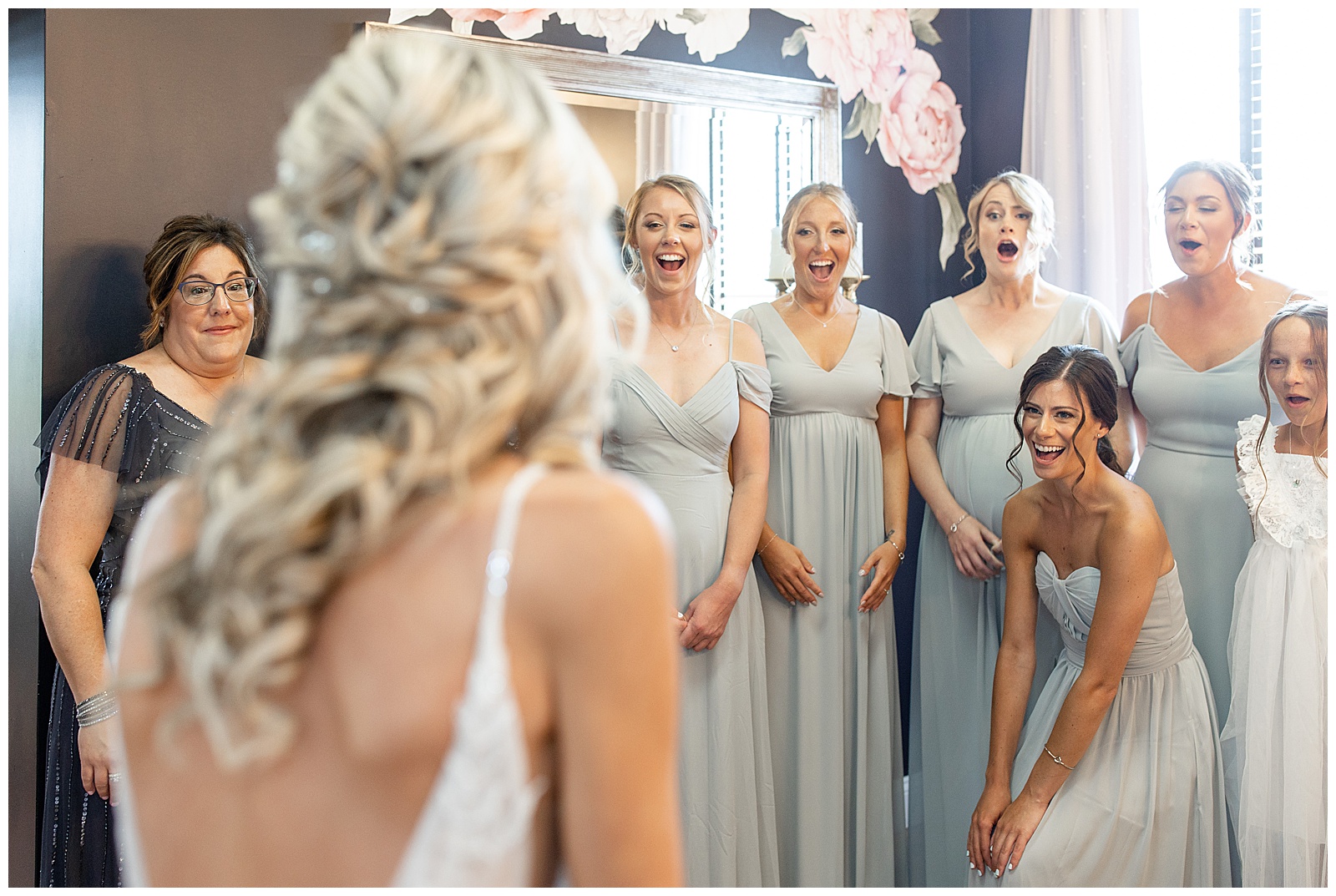 back of bride toward camera with all of the bridesmaids reacting with pure joy at their first look of her in her gown in gettysburg pa