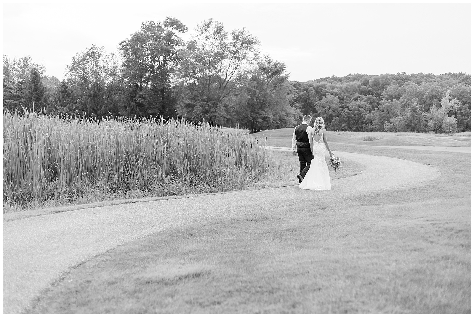black and white photo of bride and groom walking away from camera along golf path at the links at gettysburg