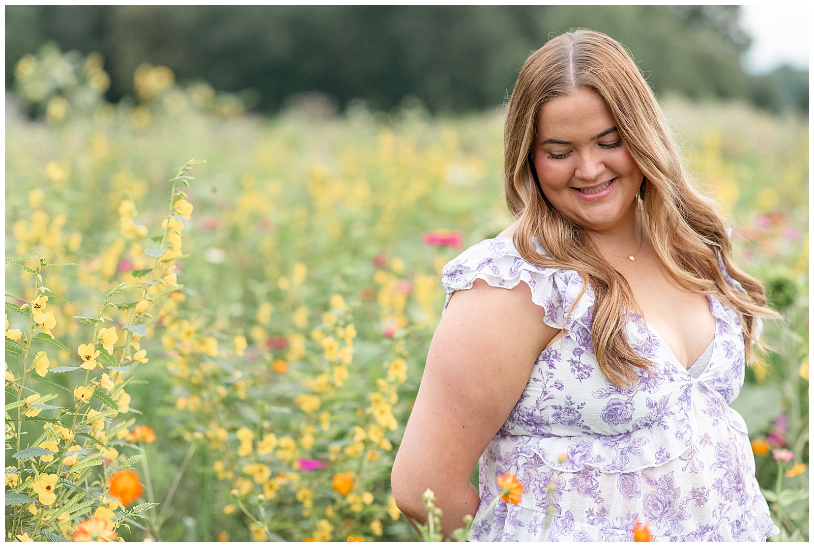 senior girl in white and purple floral top for this Cloudy Wildflower Field Senior Session