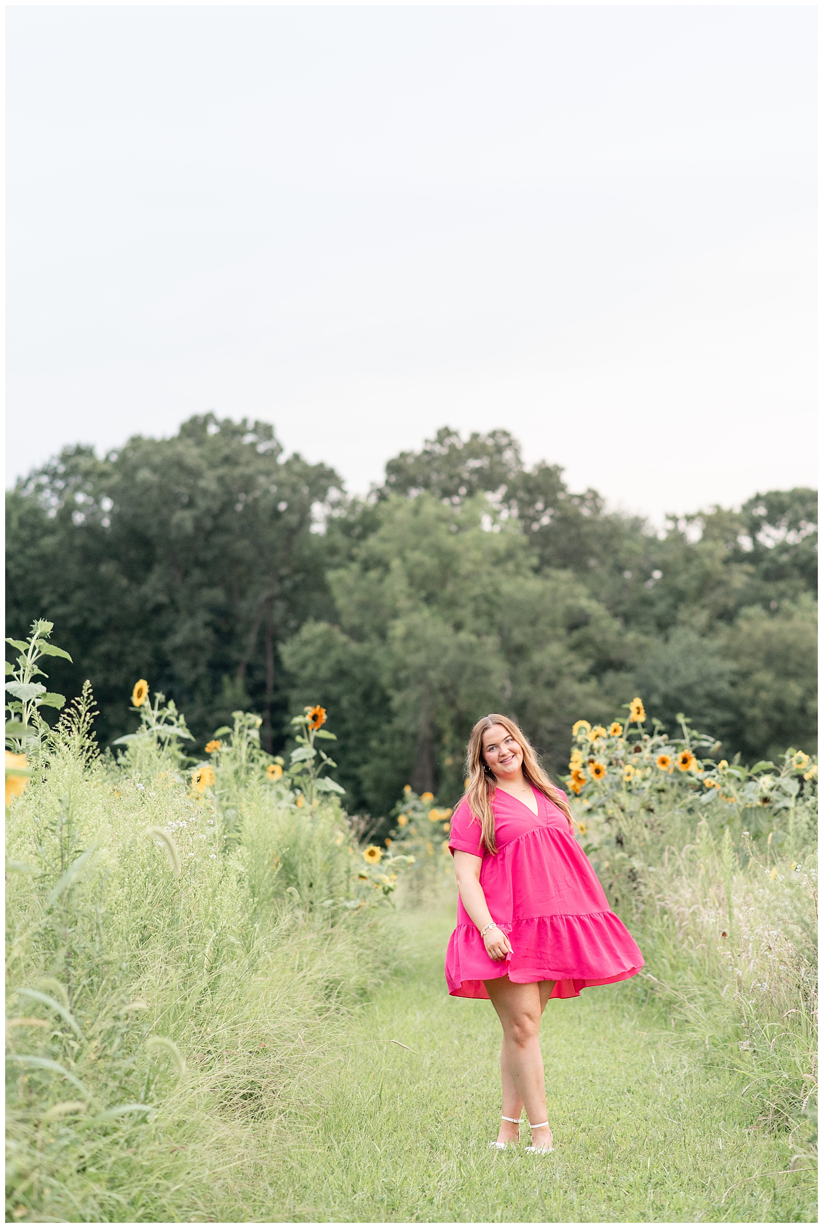 senior girl in bright magenta flowy dress in field of wildflowers in lancaster county