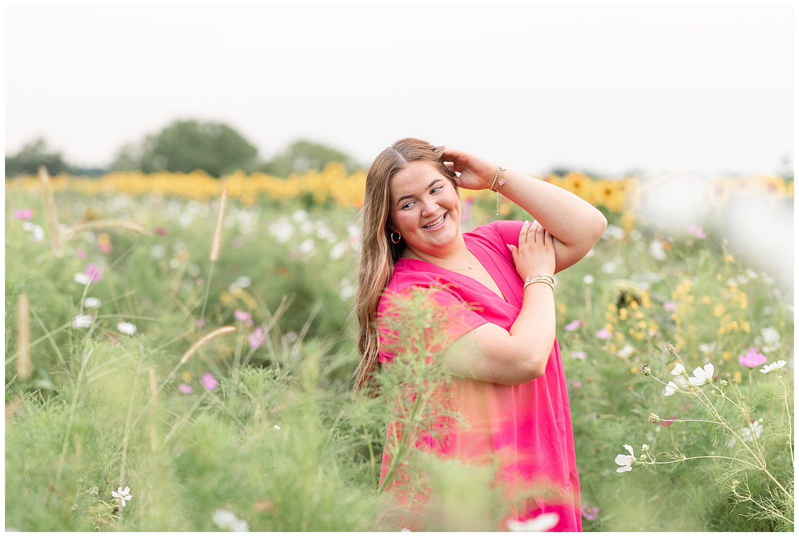 senior girl posing with left hand on temple for this Cloudy Wildflower Field Senior Session