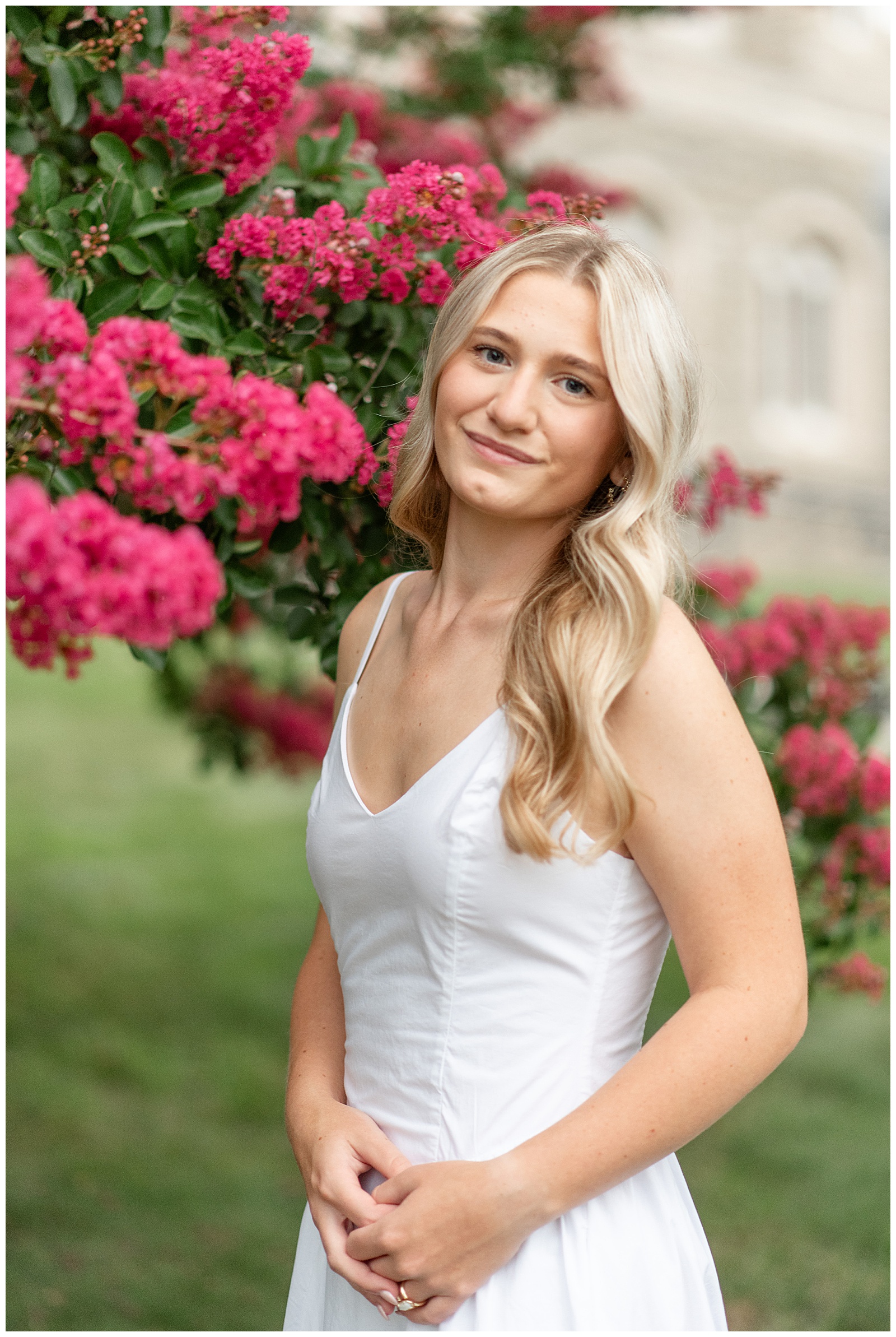 senior girl in white dress standing by dark pink blooming tree at this Masonic Village Summer Senior Session