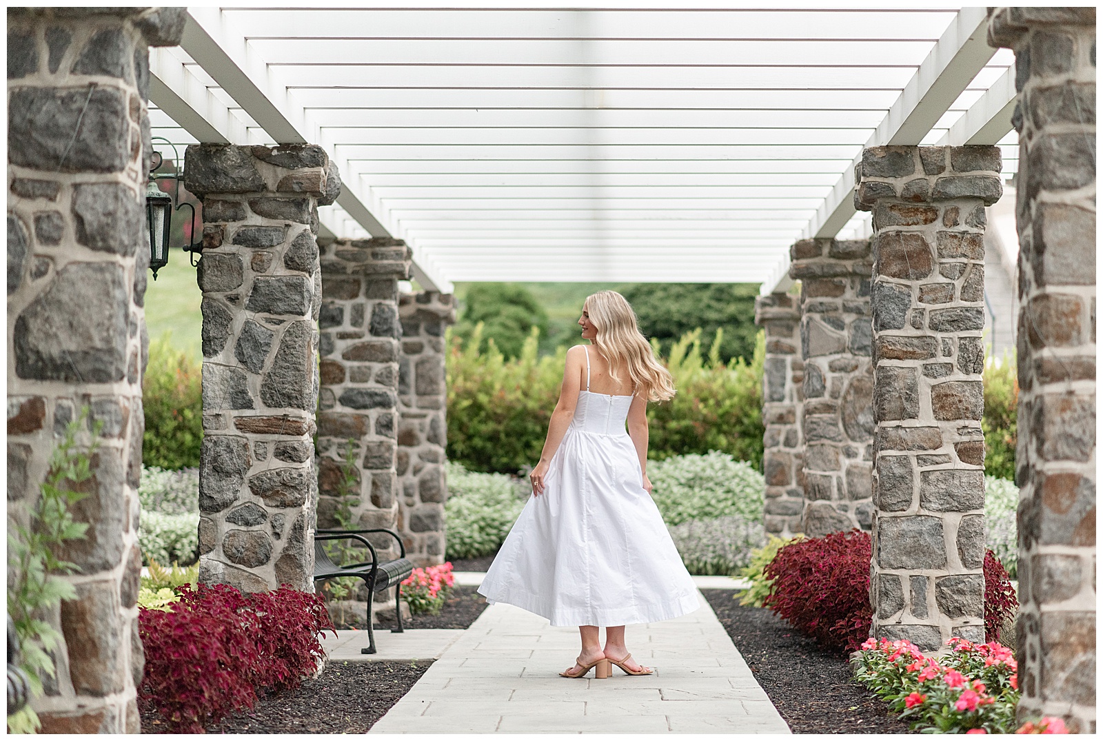 senior girl in long flowy white dress twirling under pergola at this Masonic Village Summer Senior Session