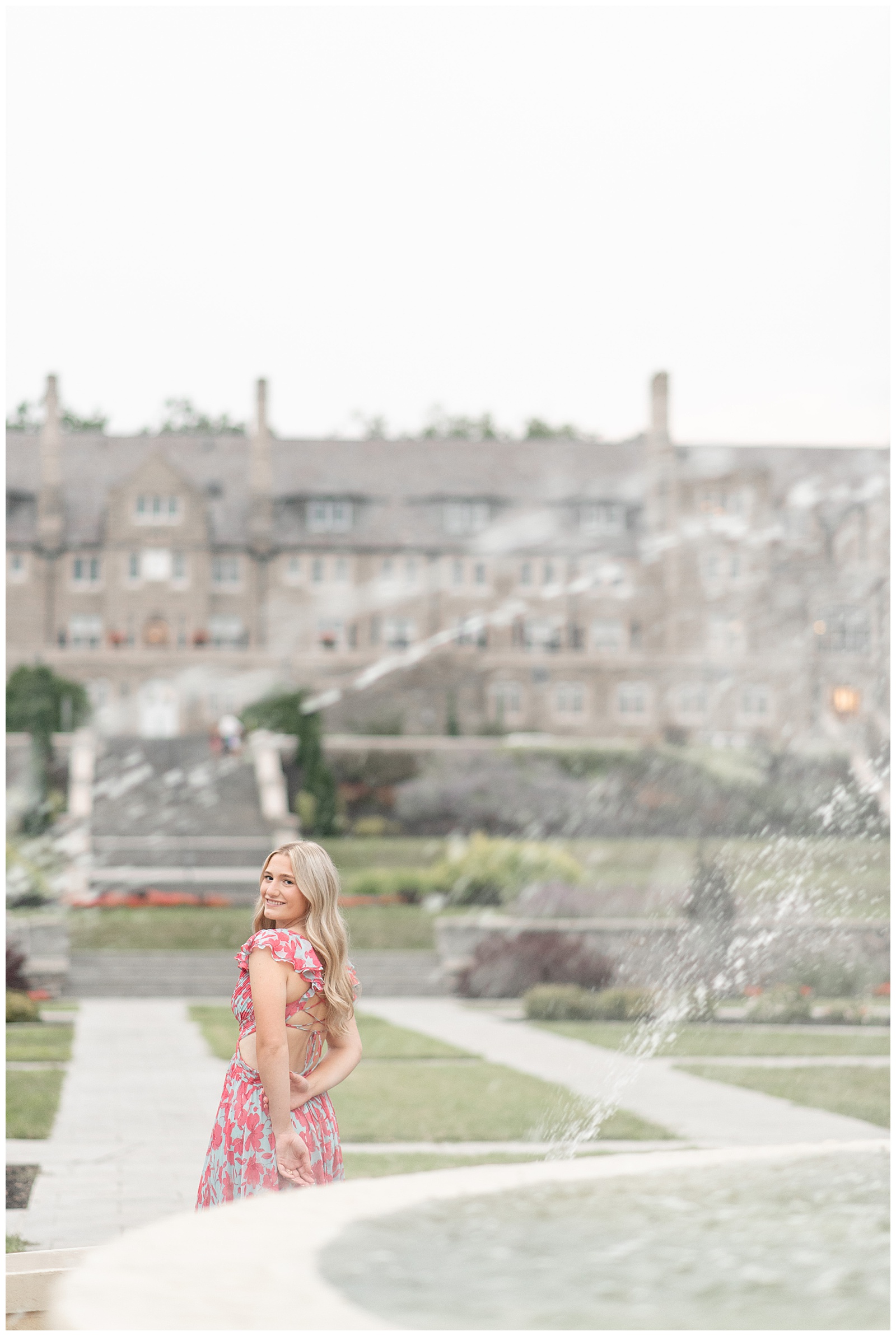 senior girl looking back over left shoulder with large building in background for this Masonic Village Summer Senior Session
