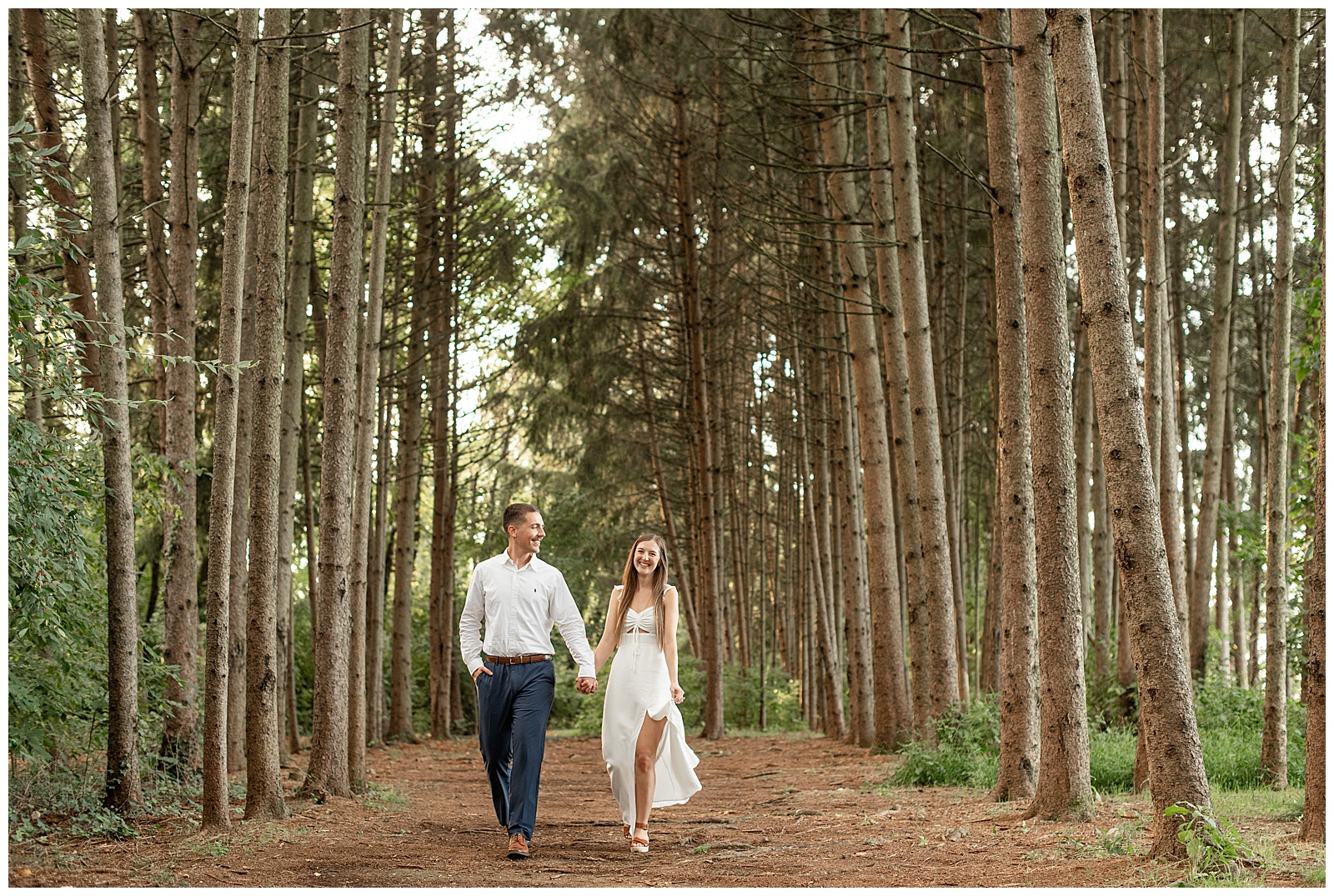 engaged couple holding hands and walking in forest at this Fall Overlook Park Engagement Session