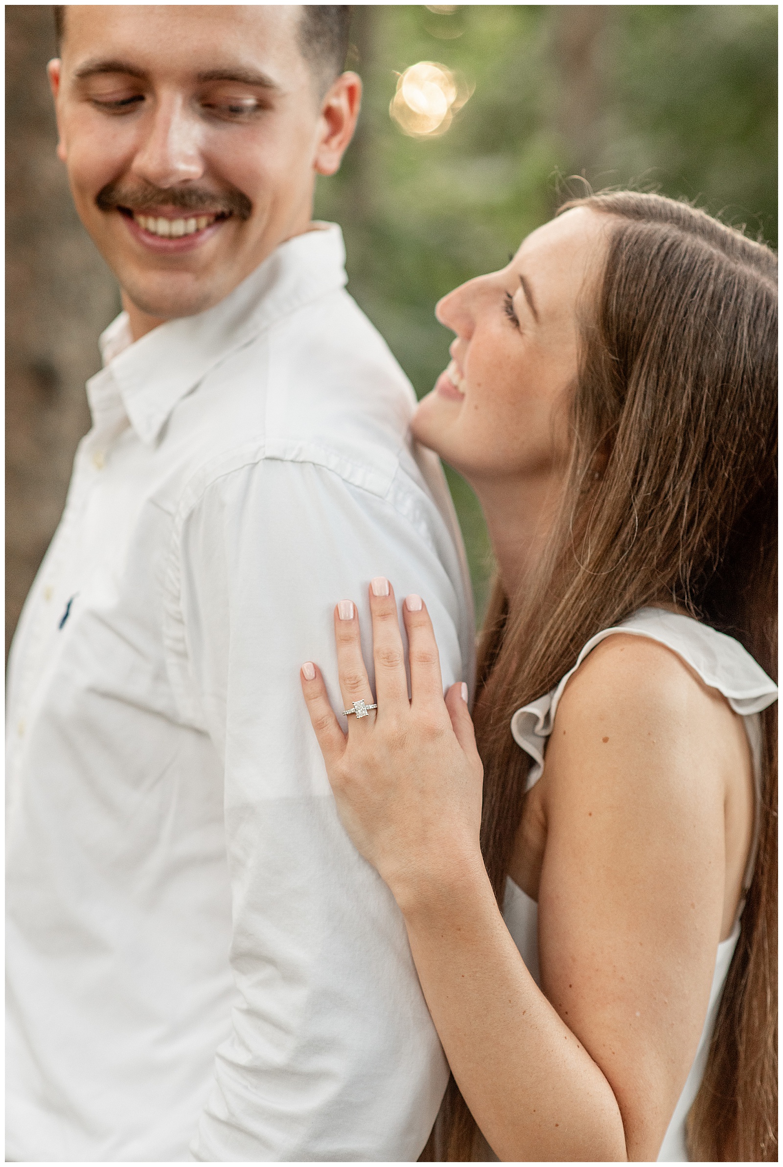 woman standing behind man as they both look at each other smiling for this lancaster county engagement session