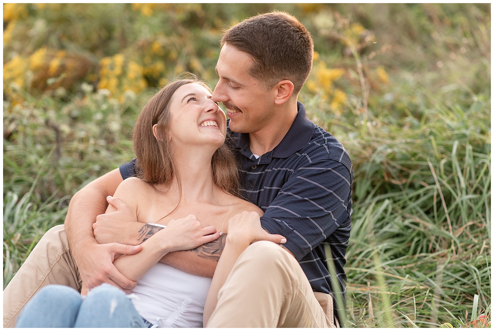 engaged couple sitting together in field of wild yellow flowers for this Fall Overlook Park Engagement Session