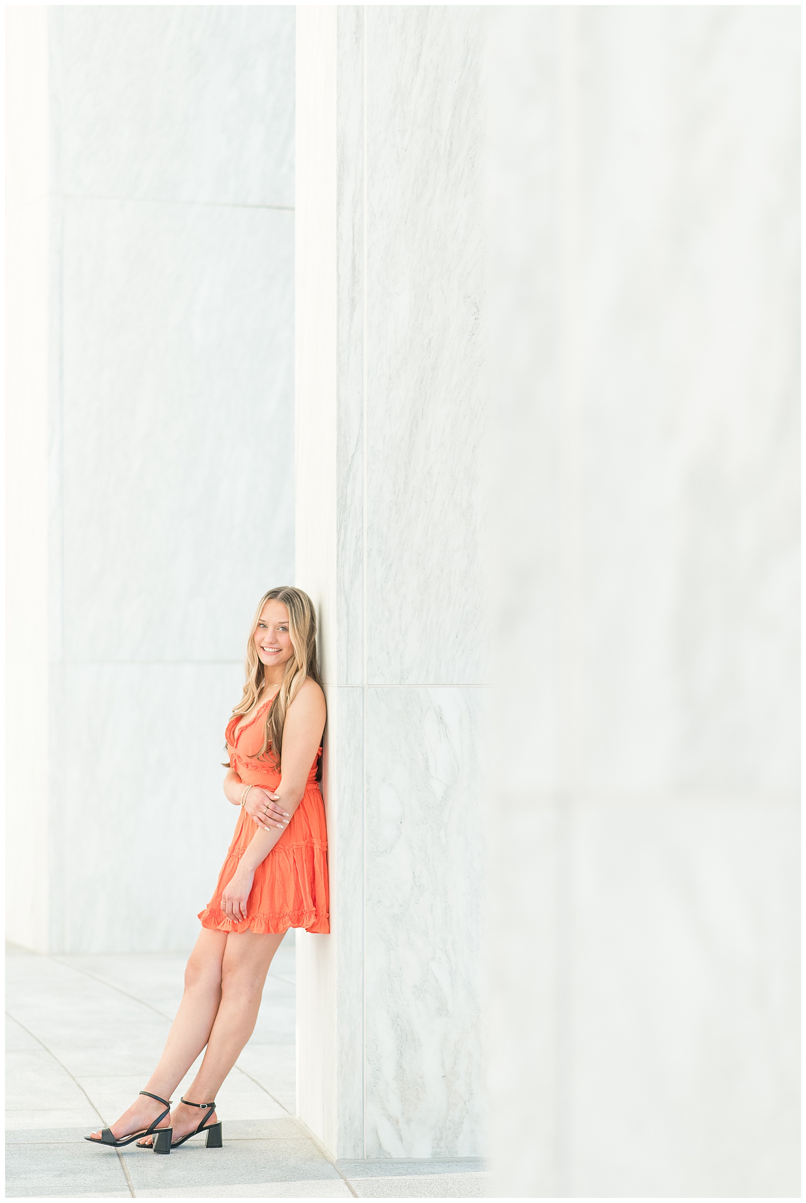 senior girl in orange dress leaning her back against concrete wall for this Founders Hall Summer Senior Session