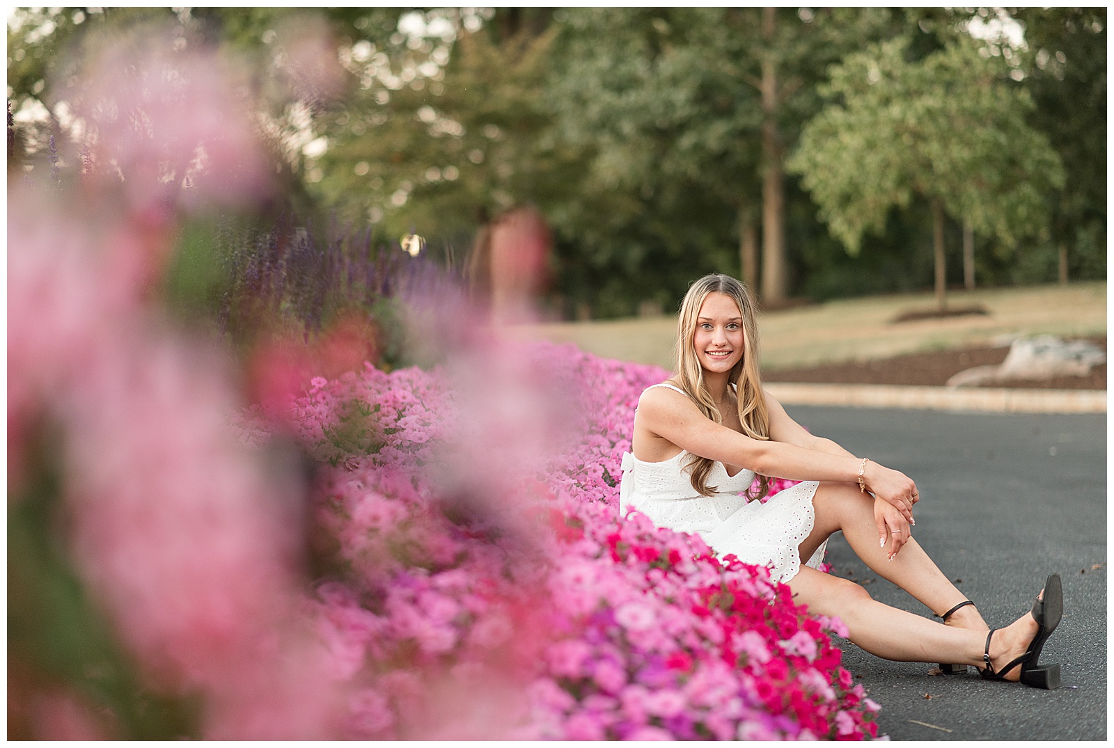 senior girl sitting on path by colorful flowers for this Founders Hall Summer Senior Session