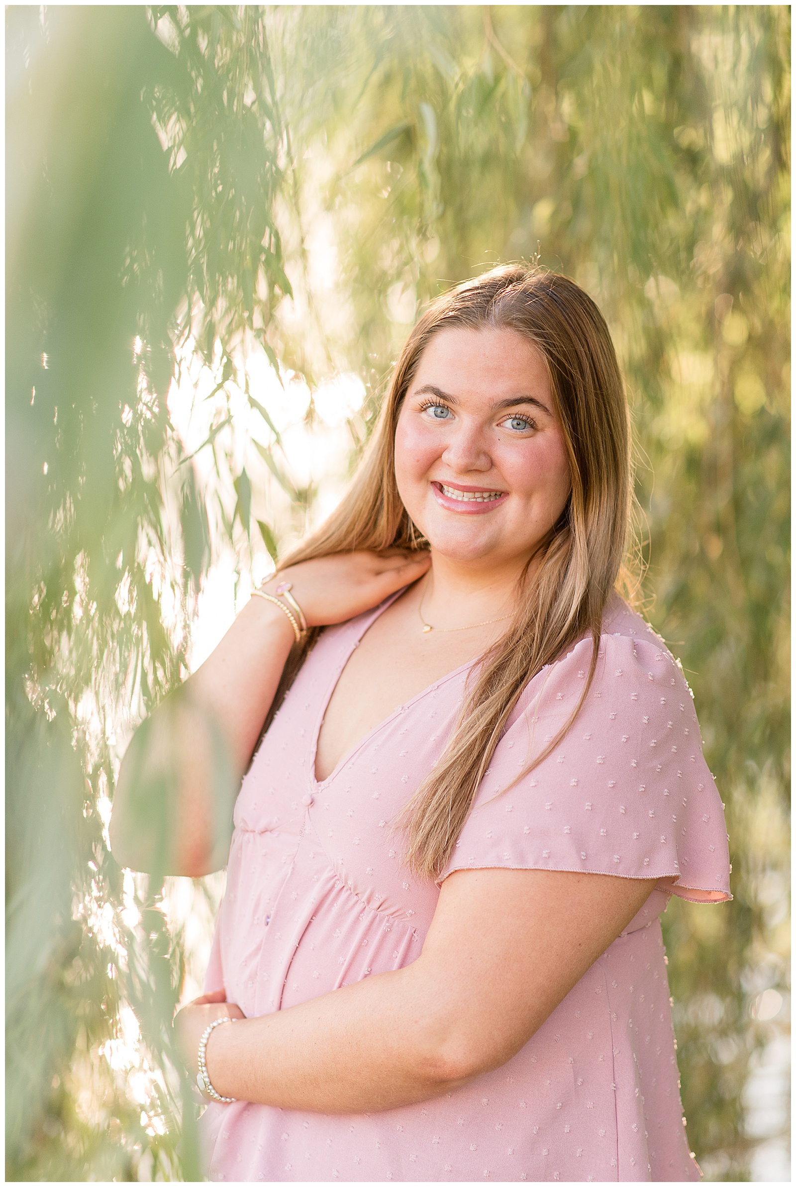 senior girl in pastel pink shirt touching her right shoulder for this Lancaster Senior Spokesmodel Mini Sessions in Greenfield Park