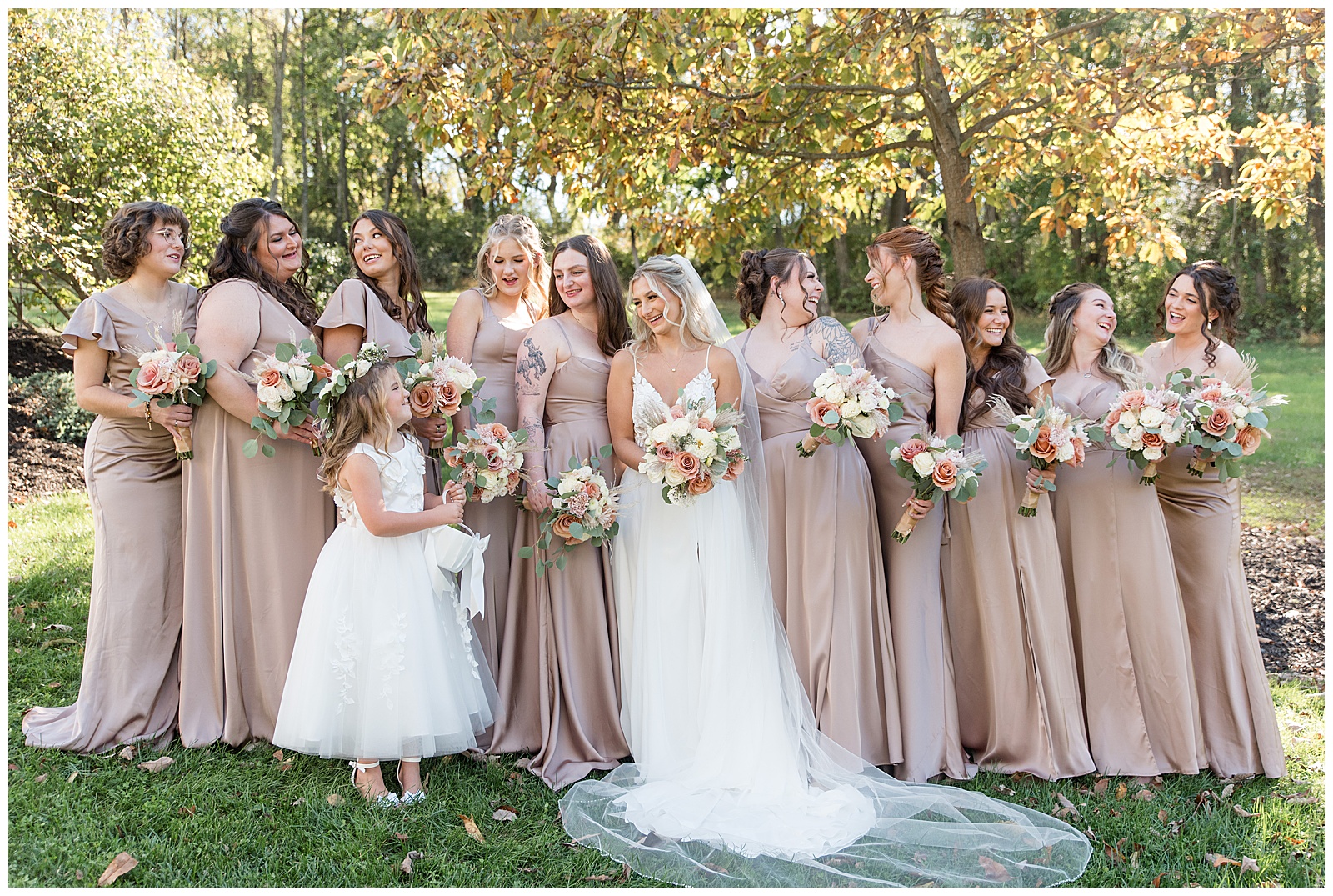 bride wearing white spaghetti strap dress with ten bridesmaids in tan dresses and one flower girl for this Central PA Farm Wedding
