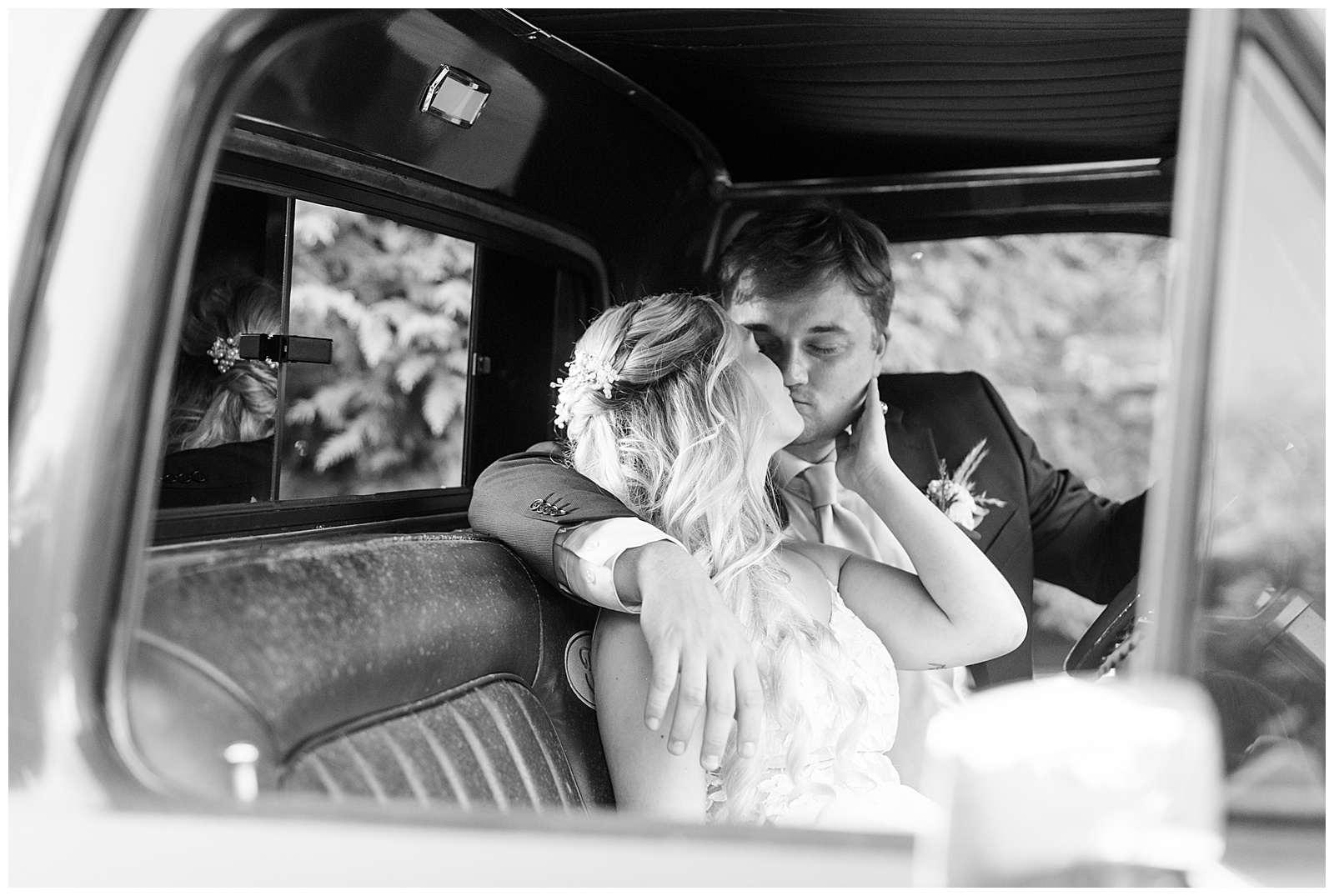 black and white photo of couple kissing in the backseat of a classic car for this Central PA Farm Wedding