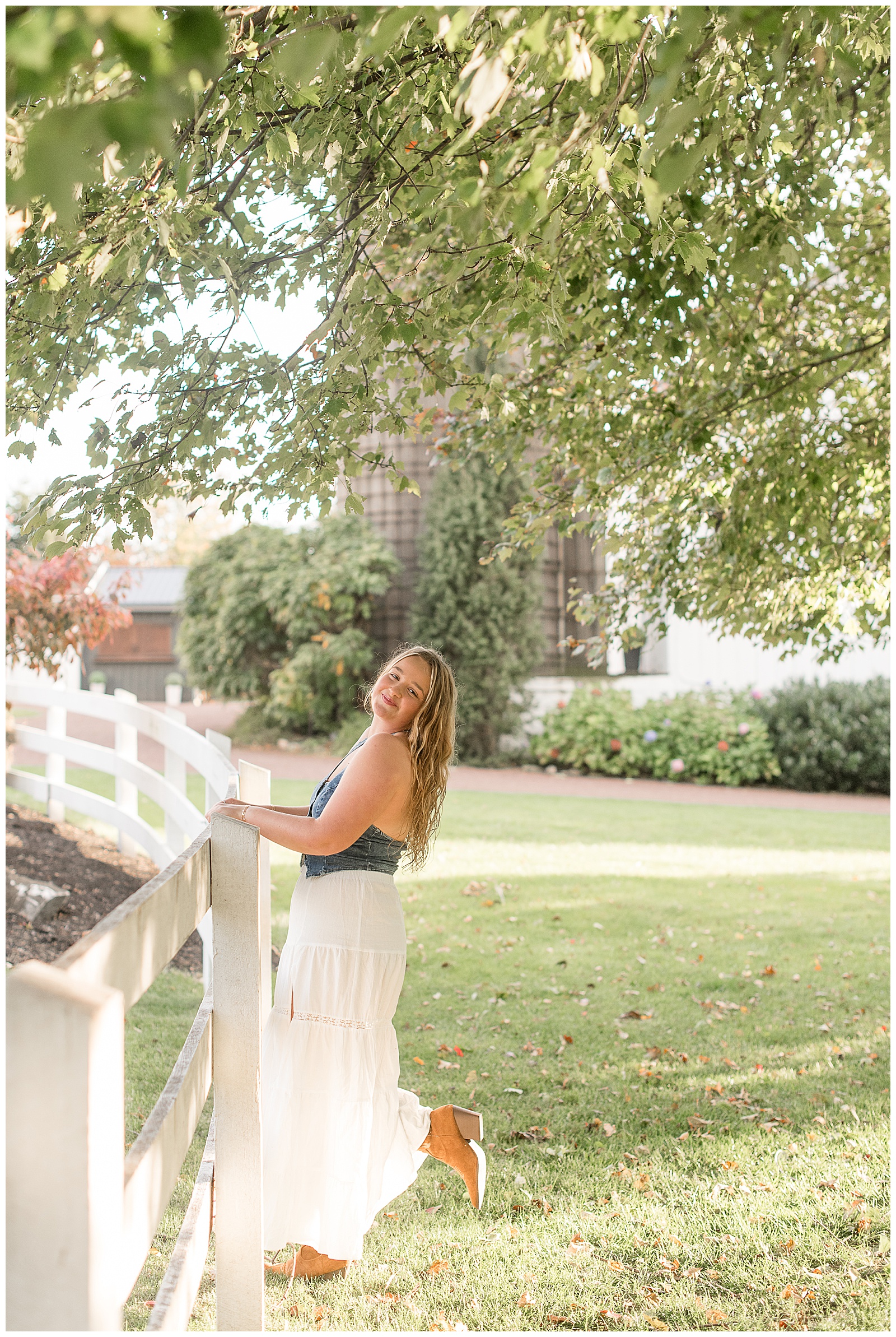 senior girl holding onto white fence and slightly leaning back for this Stoltzfus Homestead and Gardens Senior Session