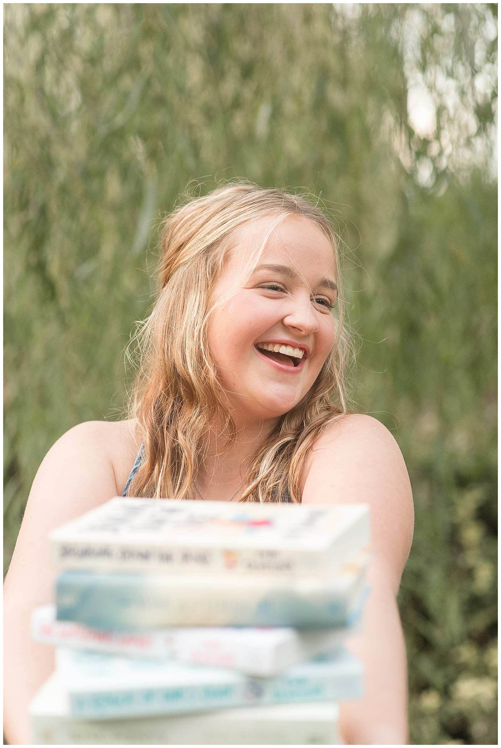 senior girl holding a stack of books and smiling big for this Stoltzfus Homestead and Gardens Senior Session