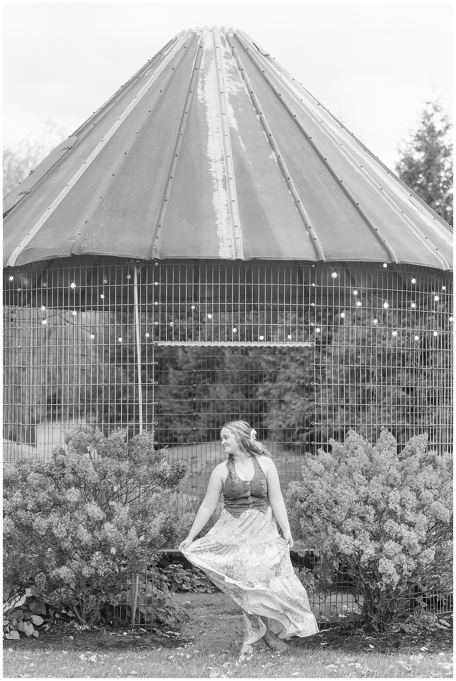 black and white photo of senior girl twirling with her dress by grain bin for this Stoltzfus Homestead and Gardens Senior Session