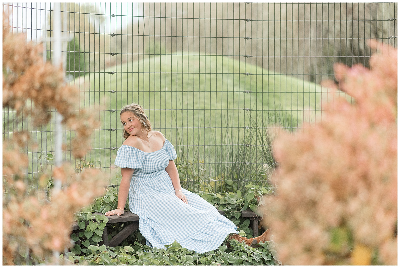 senior girl in light blue dress and cowboy boots sitting in front of grain bin for this Stoltzfus Homestead and Gardens Senior Session