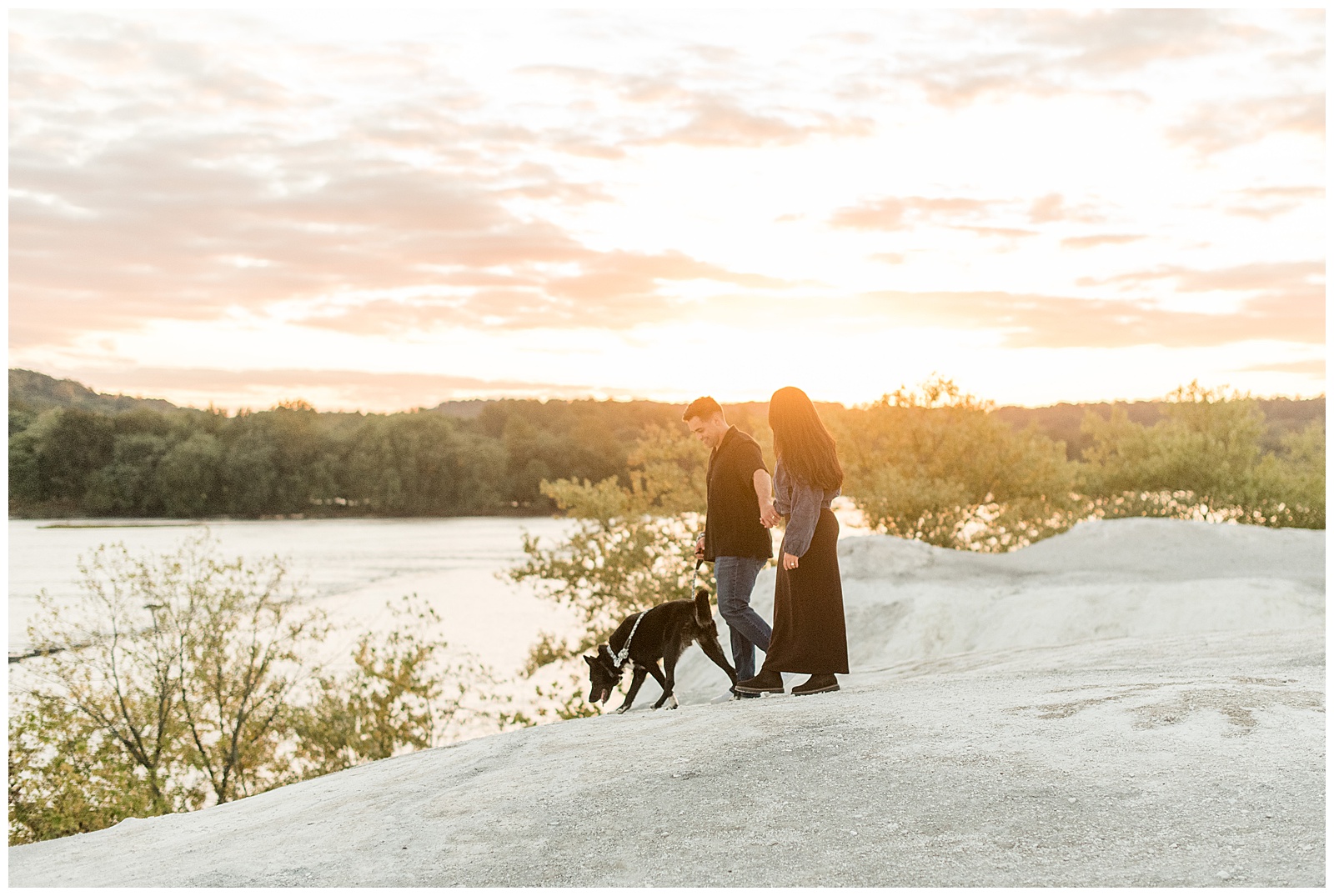 couple holding hands and walking with their pup at sunset for this White Cliffs of Conoy Fall Couples Session