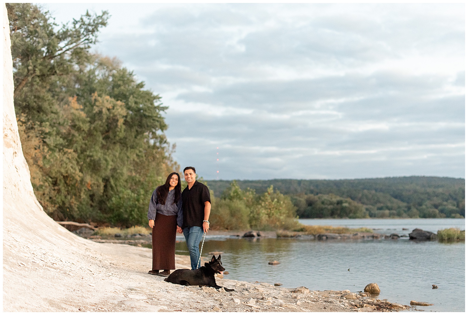 couple standing in sand with their pup along Susquehanna River for this White Cliffs of Conoy Fall Couples Session