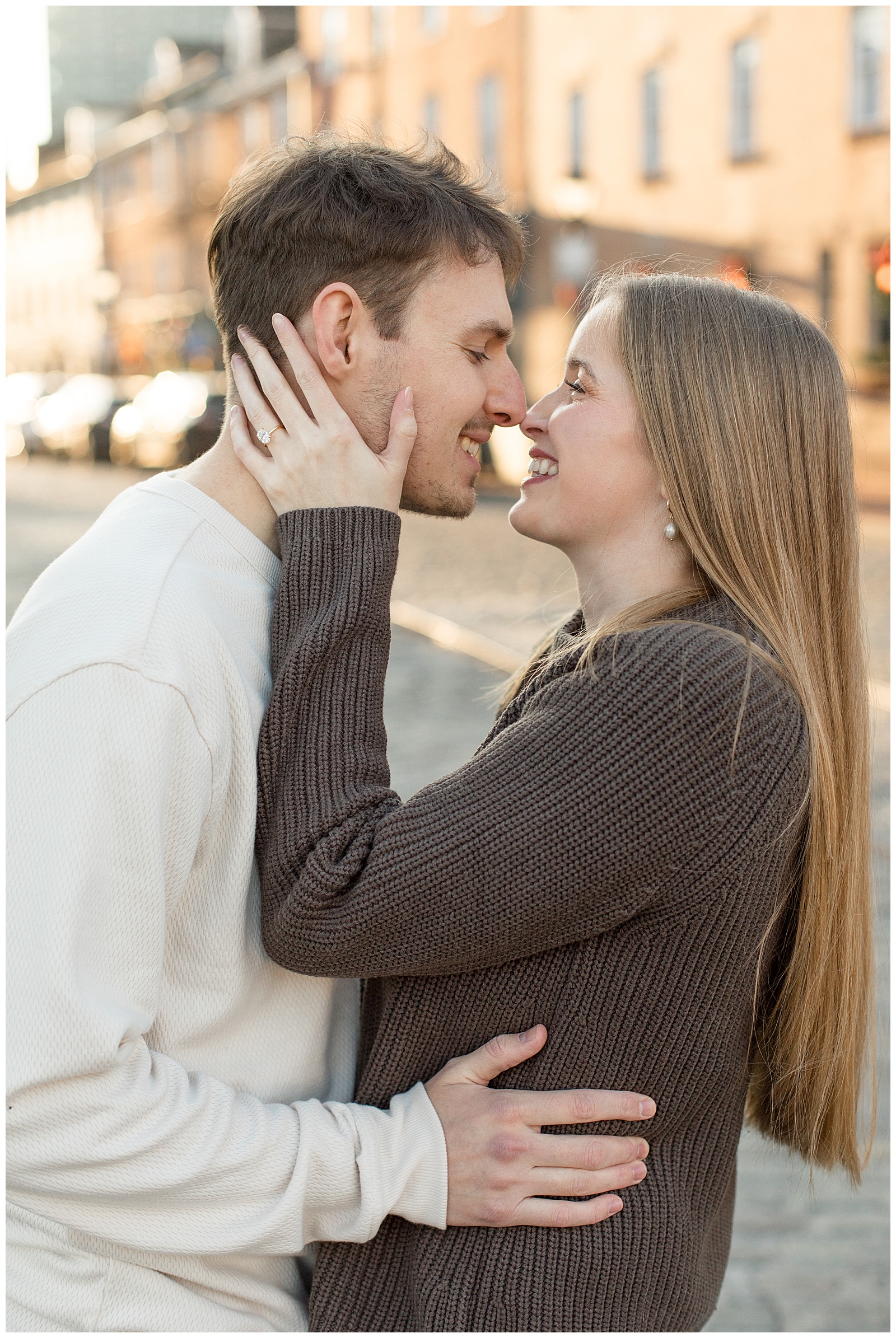 couple hugging and almost kissing with big smiles on street for this Fells Point Engagement Session
