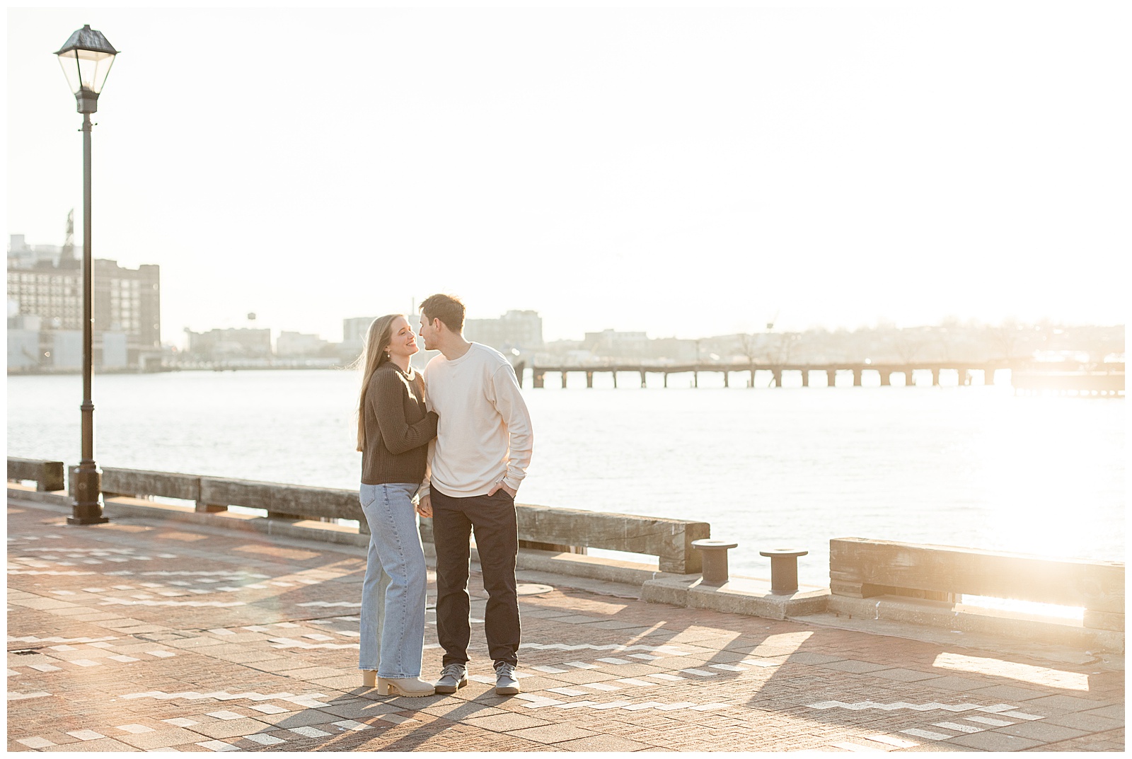 couple standing close along chesapeake bay at sunset for this winter Fells Point Engagement Session