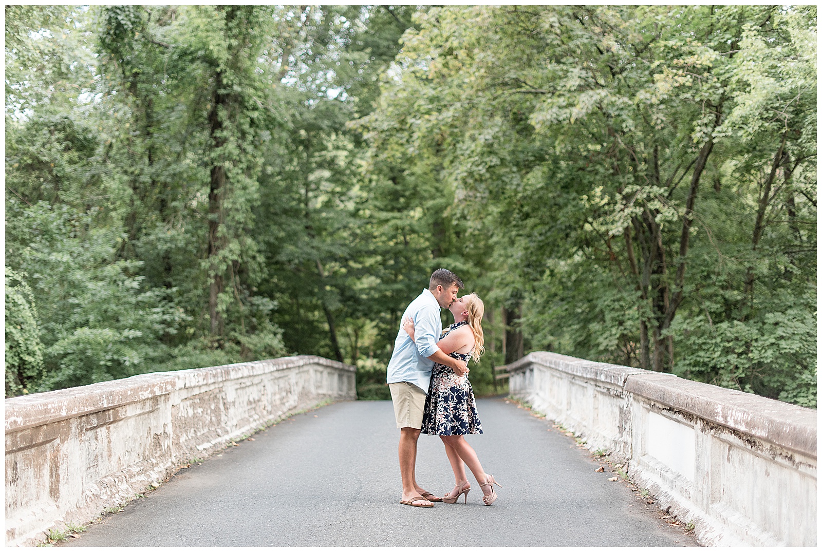 couple kissing at center of stone bridge 