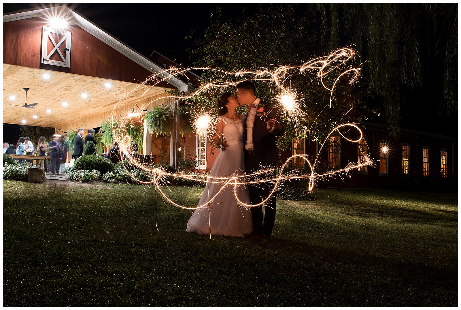 sparkler long exposure with bride and groom kissing in center