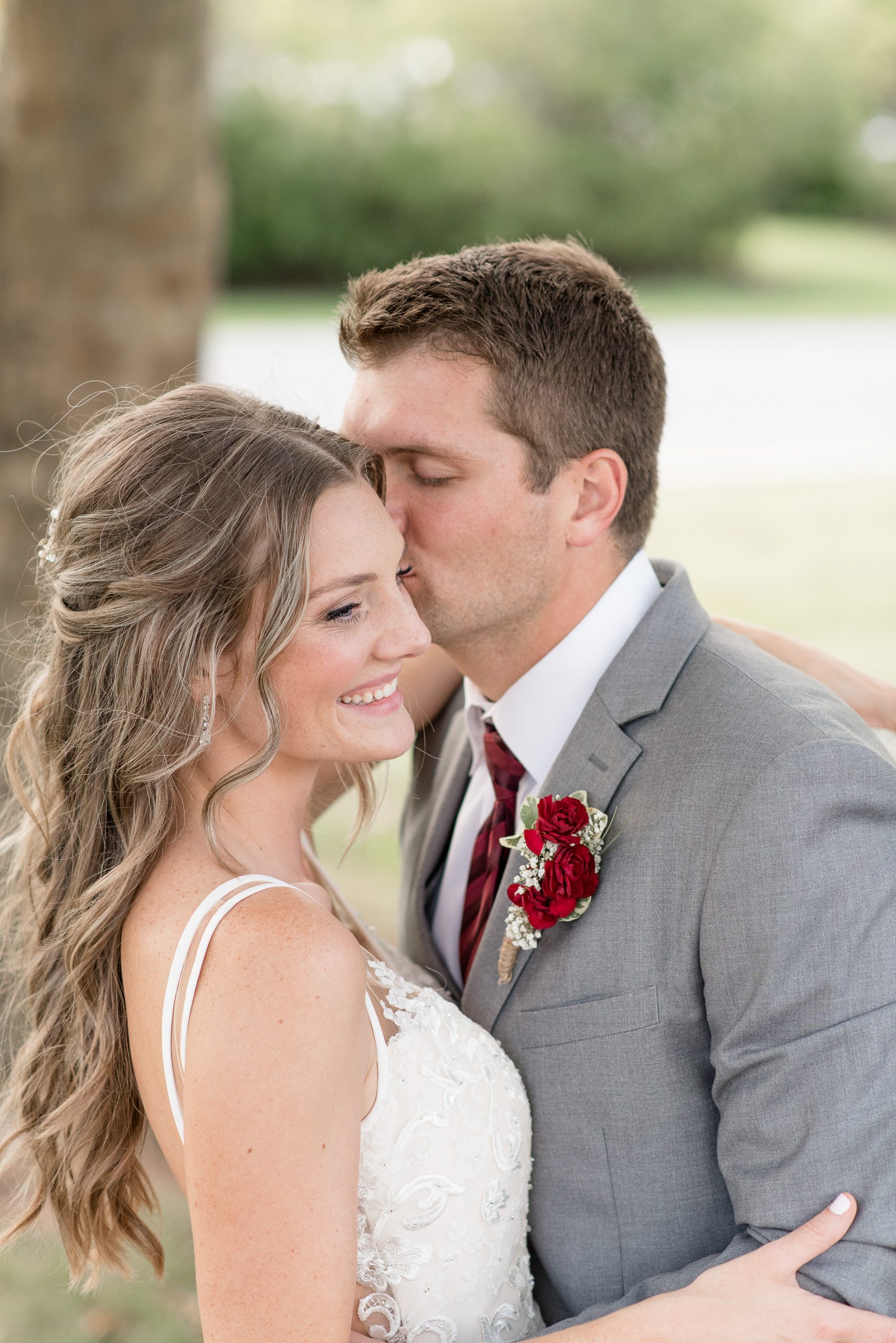 bride and groom portraits, groom kissing brides cheek and she smiles off camera