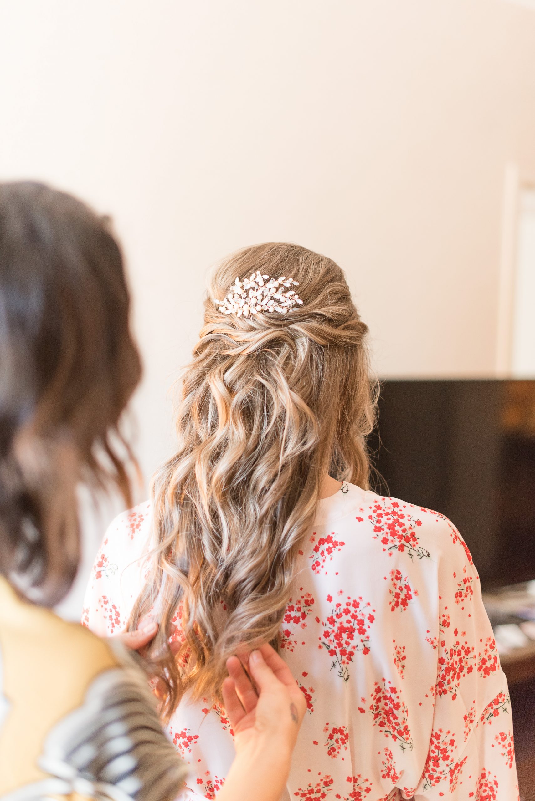 hair stylist finishing up details on bride's hair on wedding day