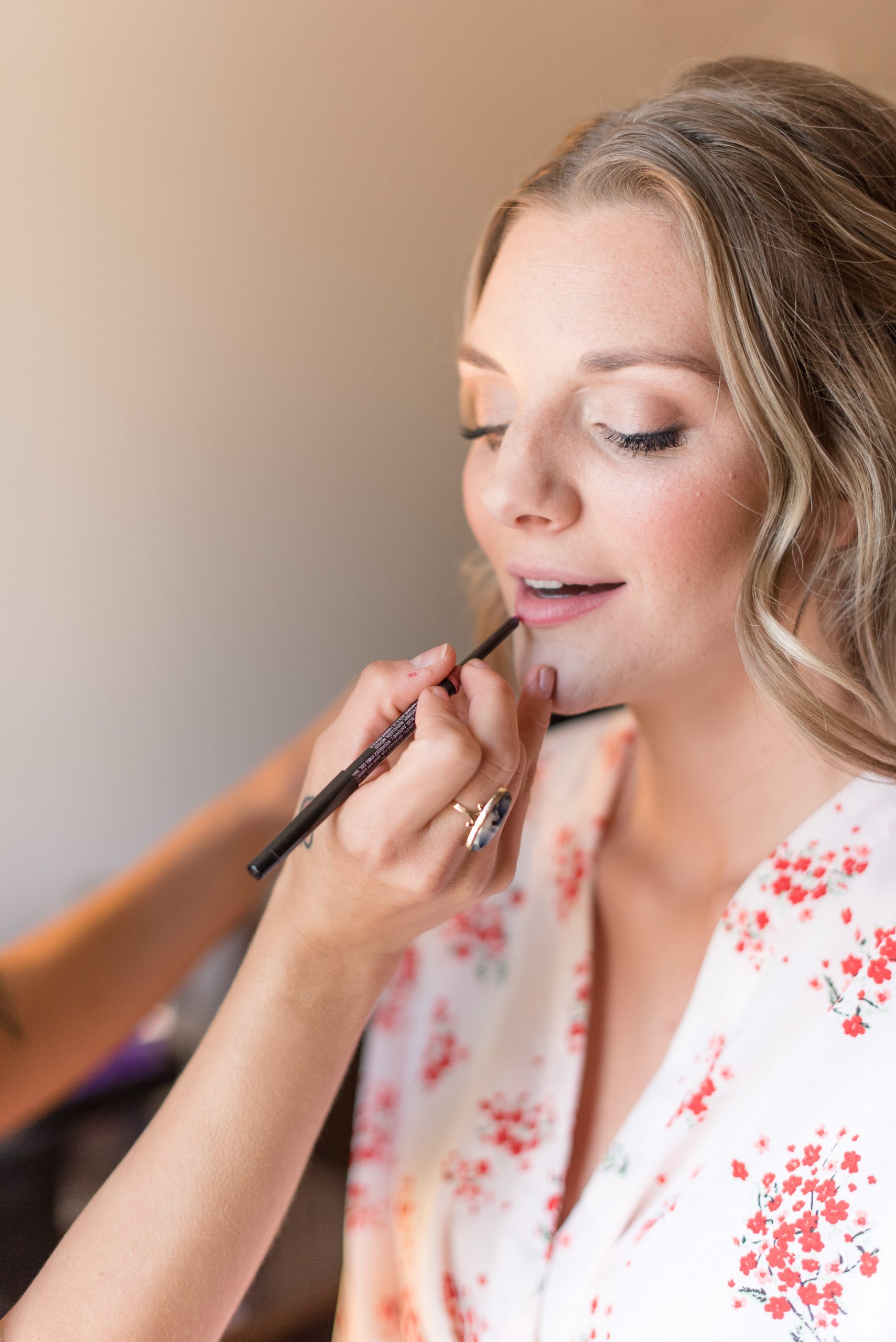 makeup artist adding last touches of lip gloss to bride