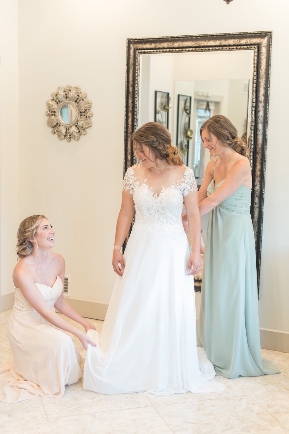 bridesmaids helping bride get into dress