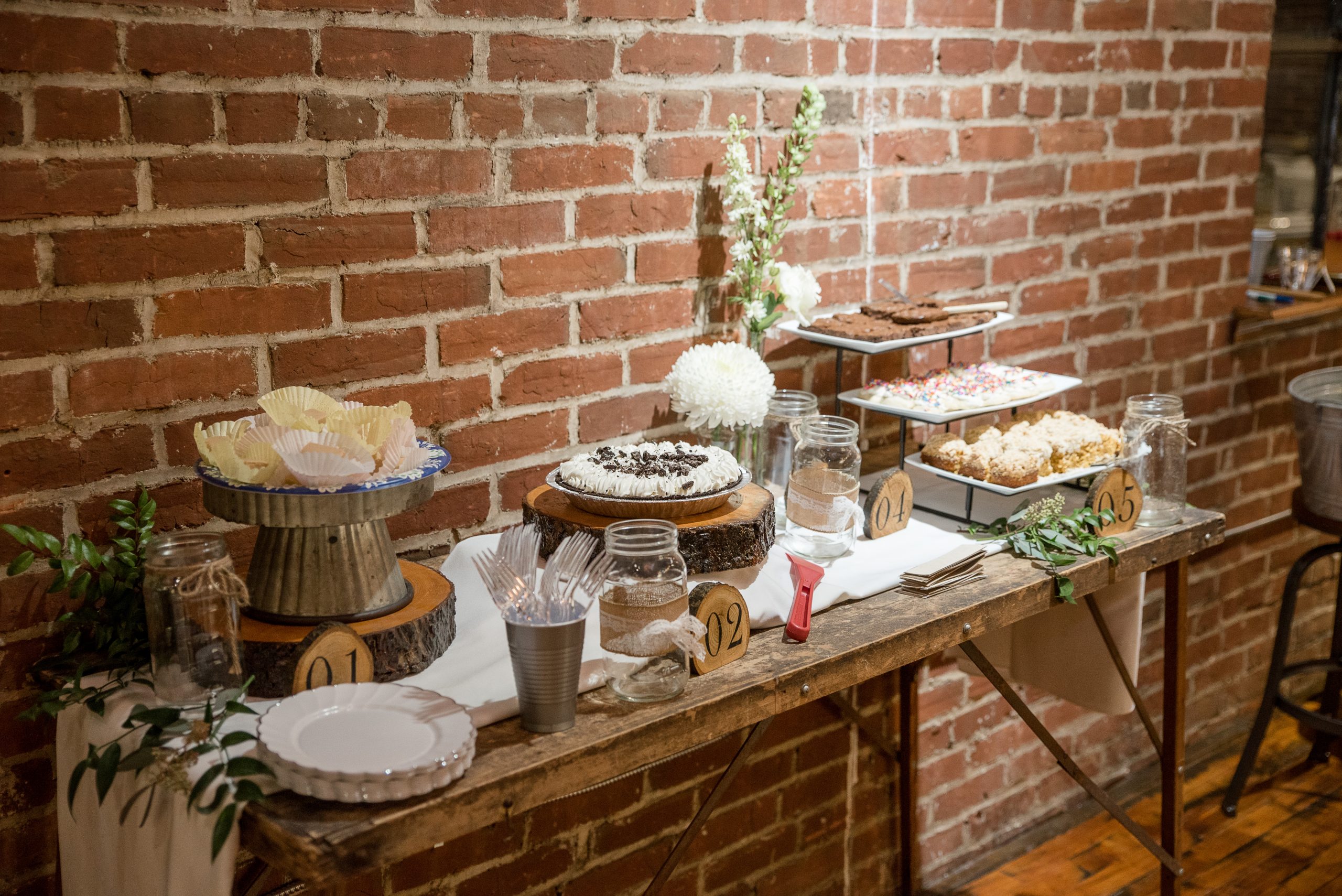 dessert table on old wallpaper table in front of brick wall