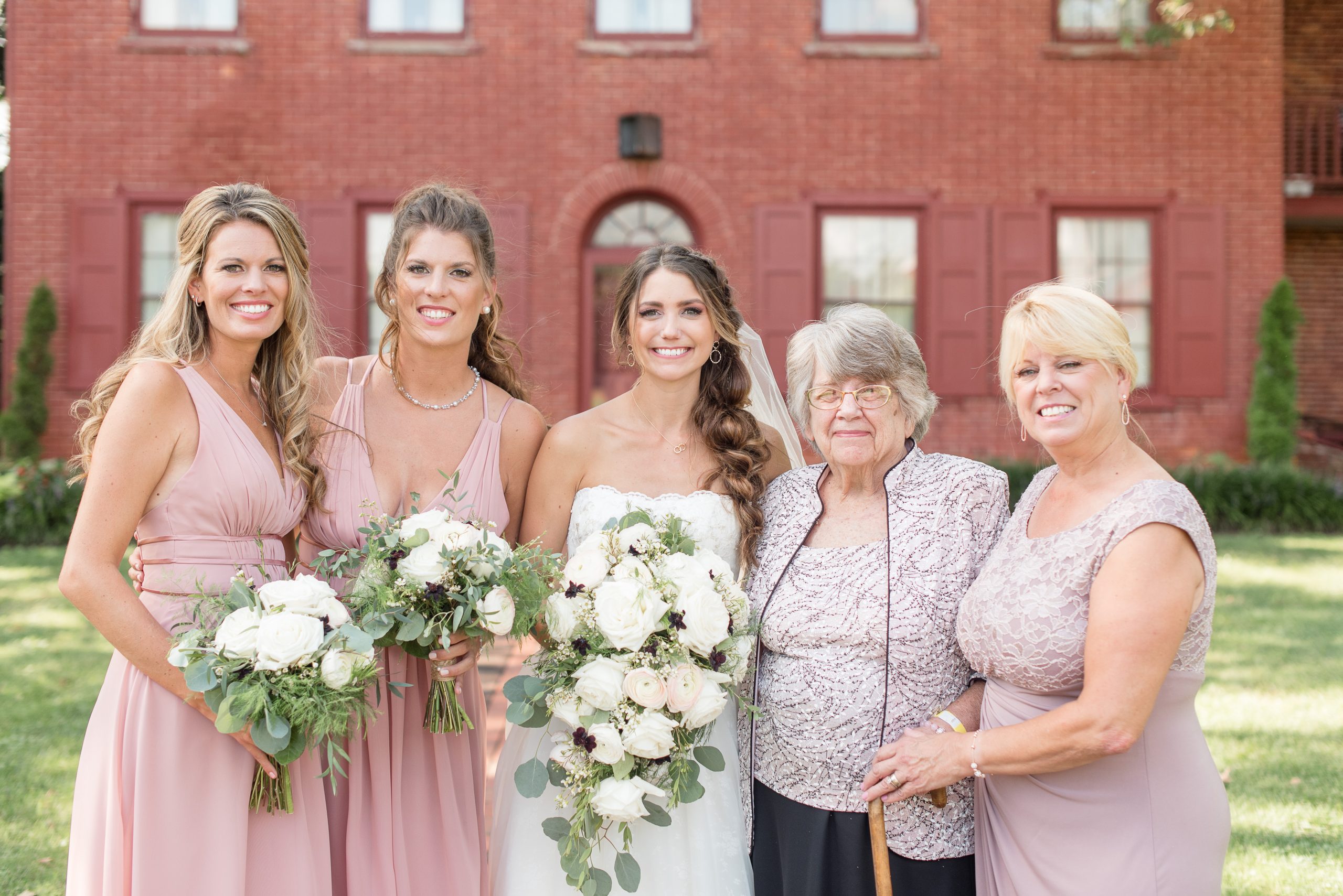 family formal of three generations of women in family in front of brick house