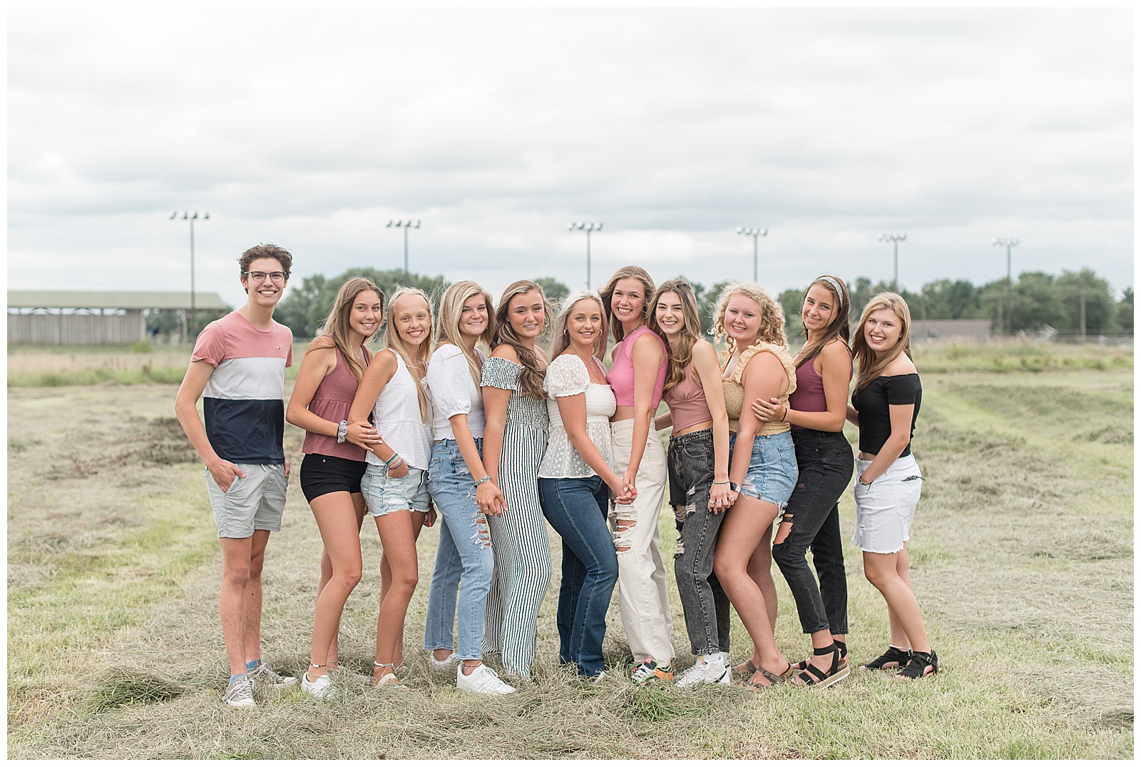 eleven senior spokesmodels angled toward each other in field smiling at the camera on overcast day in lancaster pennsylvania