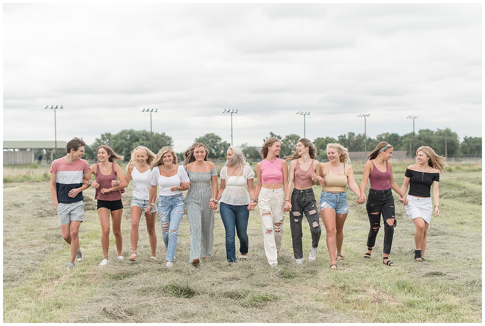 eleven senior spokesmodels smiling and looking at each other while walking in field toward camera in lancaster pennsylvania