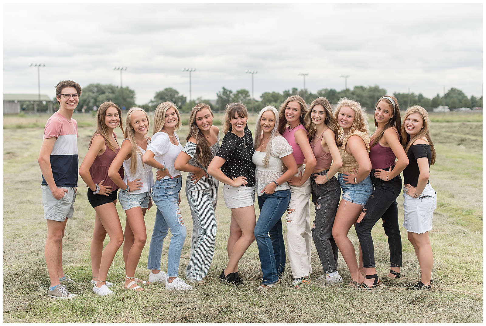 photographer surrounded by eleven senior spokesmodels in grassy field on overcast day in lancaster pennsylvania